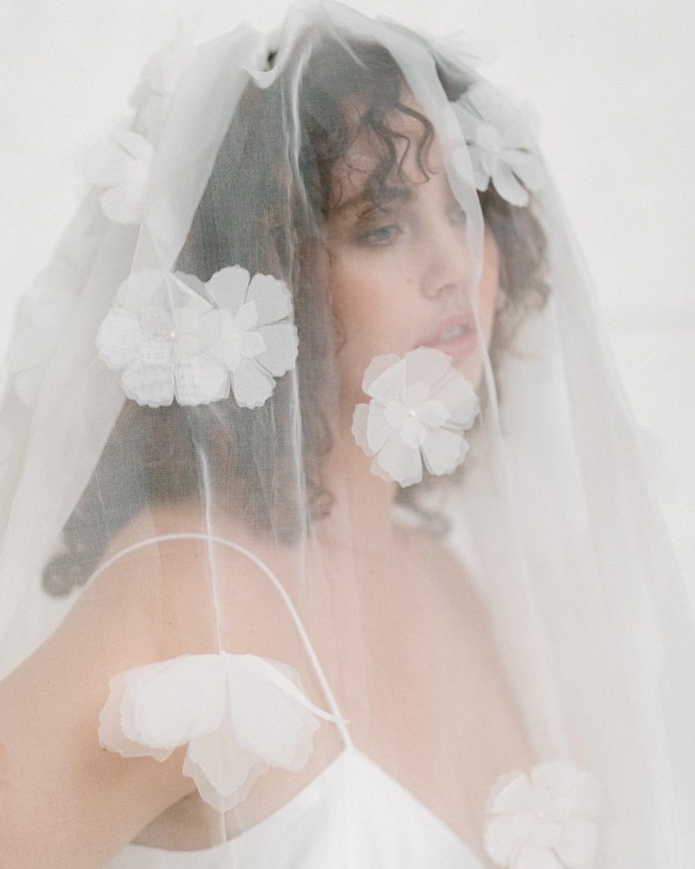 The Emma veil is a real statement piece. Silk organza is secured via a comb to the top of the head to cocoon the body and gather at the hem. 

Hand made silk organza flowers - all repurposed from off-cuts - are an optional adornment. Wear it ruched o