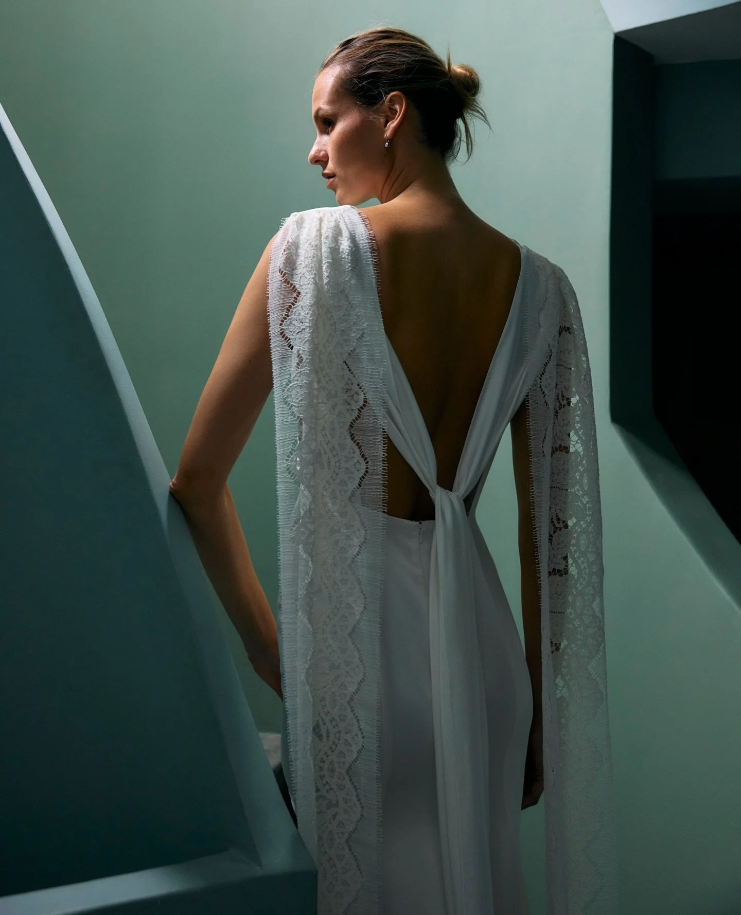 A study in contrasts, the Astra dress balances precision and poetry.⁠
⁠
A softly bloused bodice with a high boat neckline falls into a fluid fit-and-flare silhouette that moves with quiet ease. Draped lace swags cascade from the shoulders to the floo