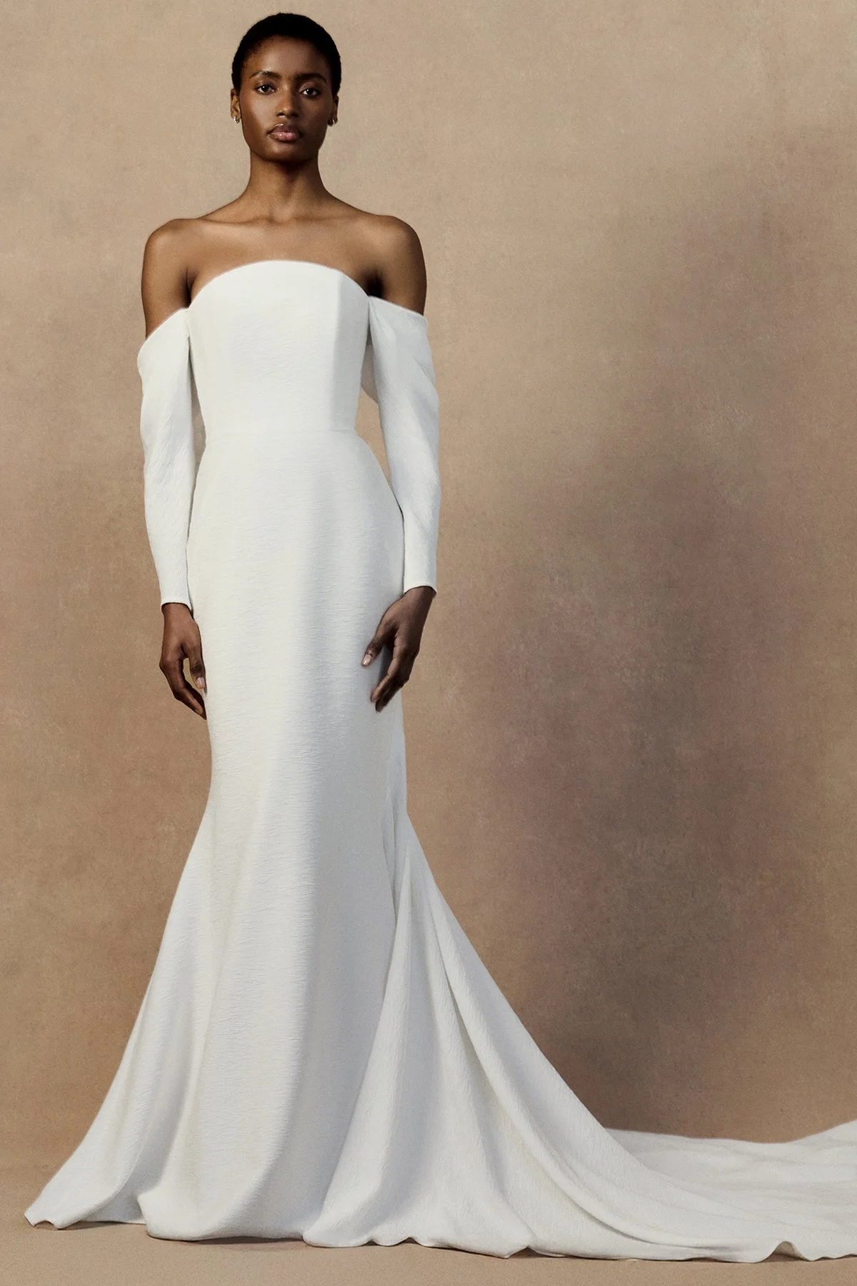 front image of white wedding gown nicole dress in plissé-textured cloqué featuring a curved upward neckline with draped long sleeves.