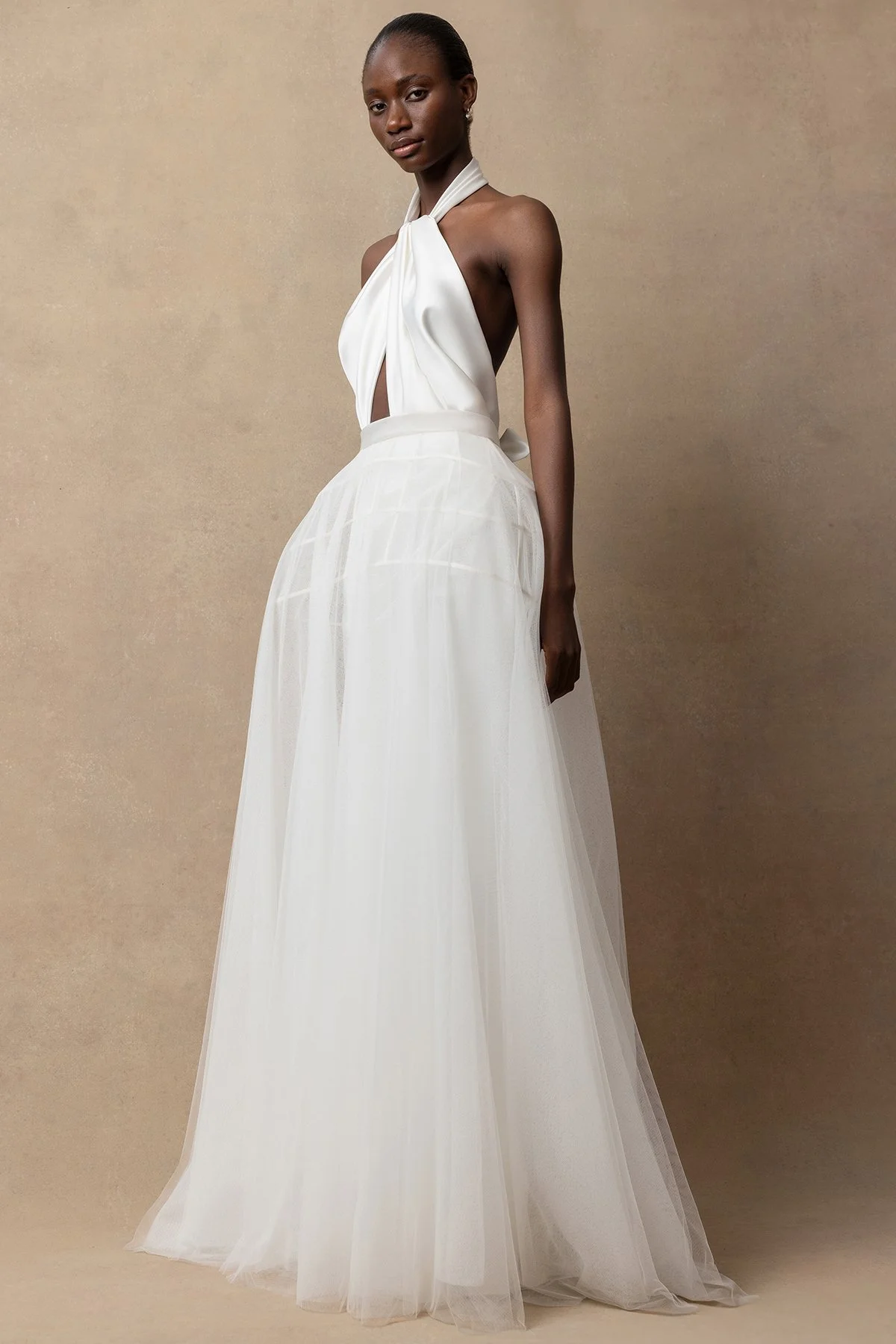 Izy wedding dress with halterneck, bias-cut slinky fabric, twisted drape front, closed back buttons, low back ties, and fit-and-flare silhouette. With the Seren skirt