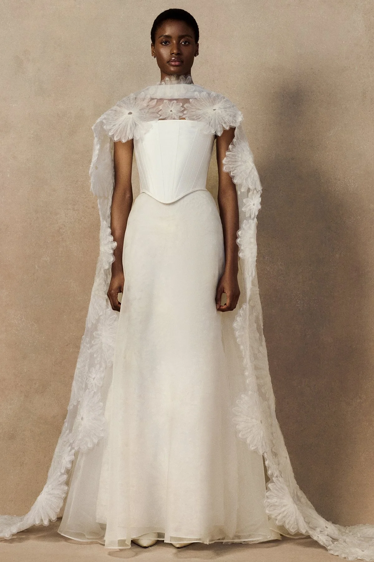 front image of Meg bridal skirt with looped daisies in raw-edged silk organza, and a layered silk organza fit-and-flare skirt. with phoenix corset and fig cape