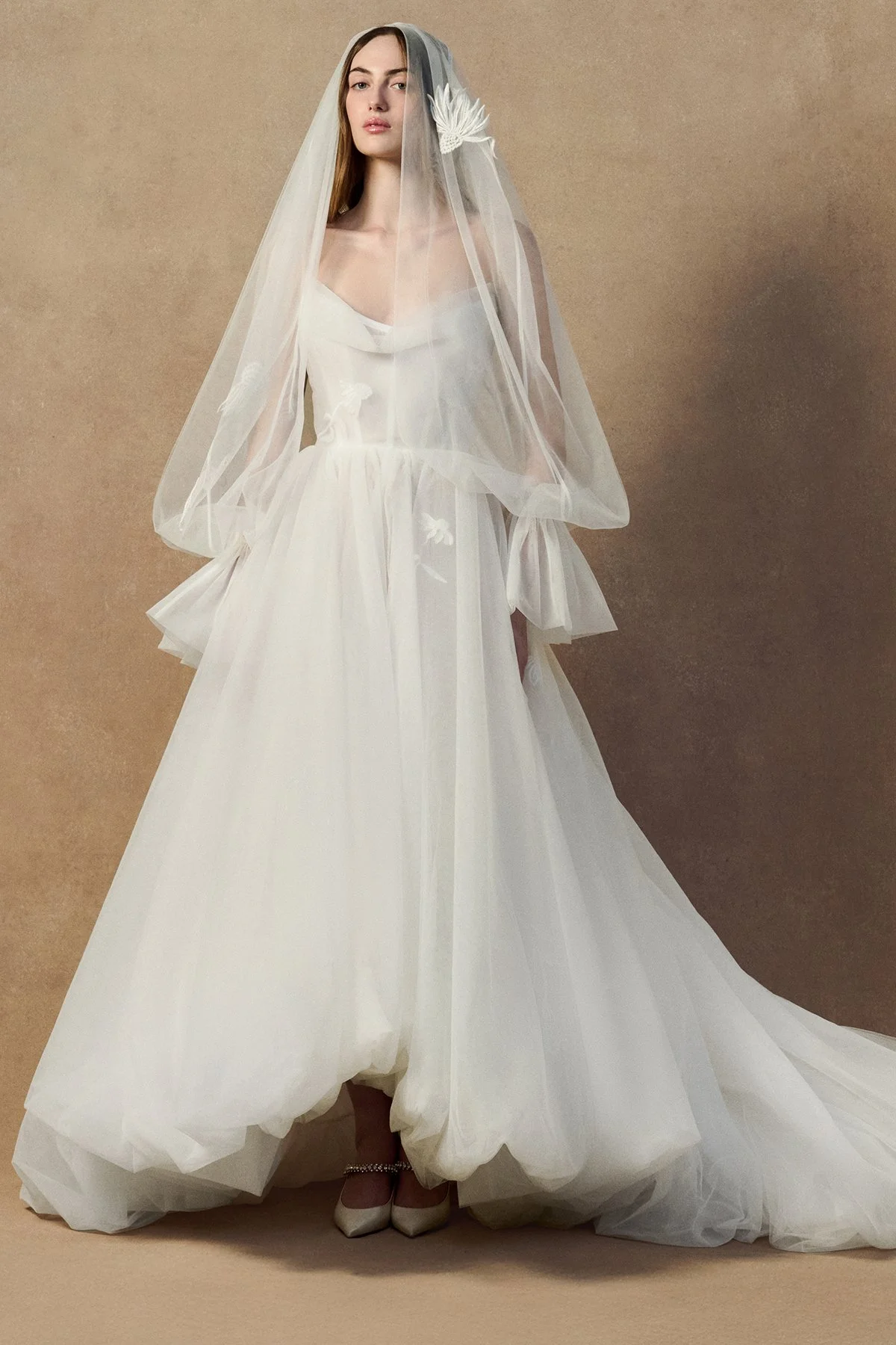 front images of the Kerry Veil in double-layered tulle with a voluminous sheer silhouette that drapes over the head and shoulders to gather at the wrist creating sleeves