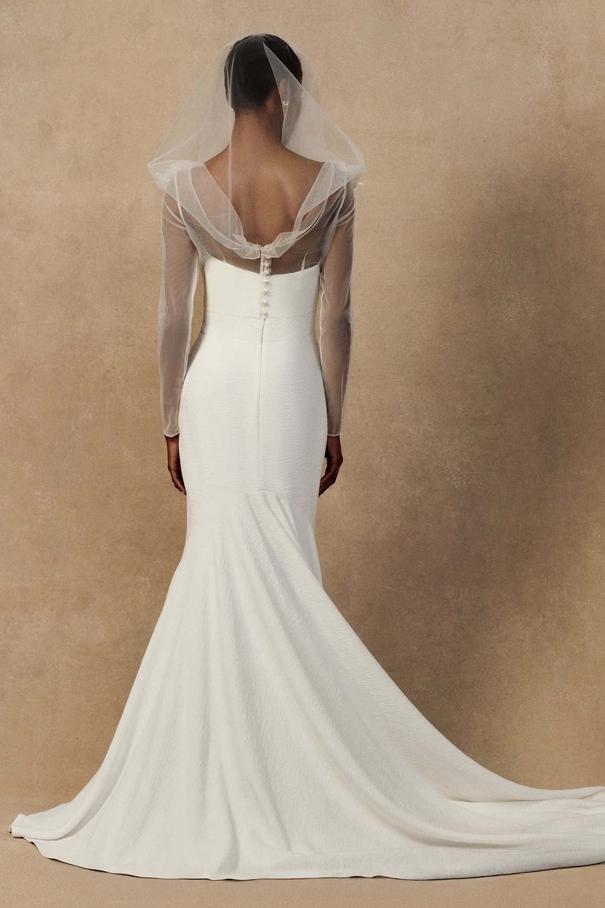 back image of white wedding gown nicole dress in plissé-textured cloqué featuring a curved upward neckline . with Geum sleeved and hooded jacket