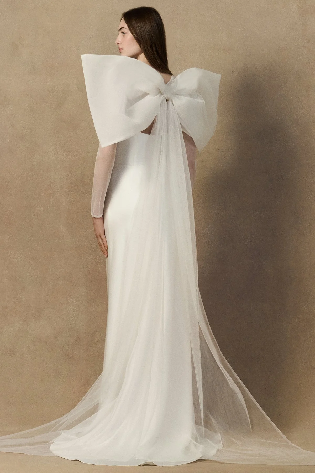 back image of oversized bridal bow jacket crafted from layered tulle, organza, and crinoline, styled as a sheer bolero. worn with herah dress