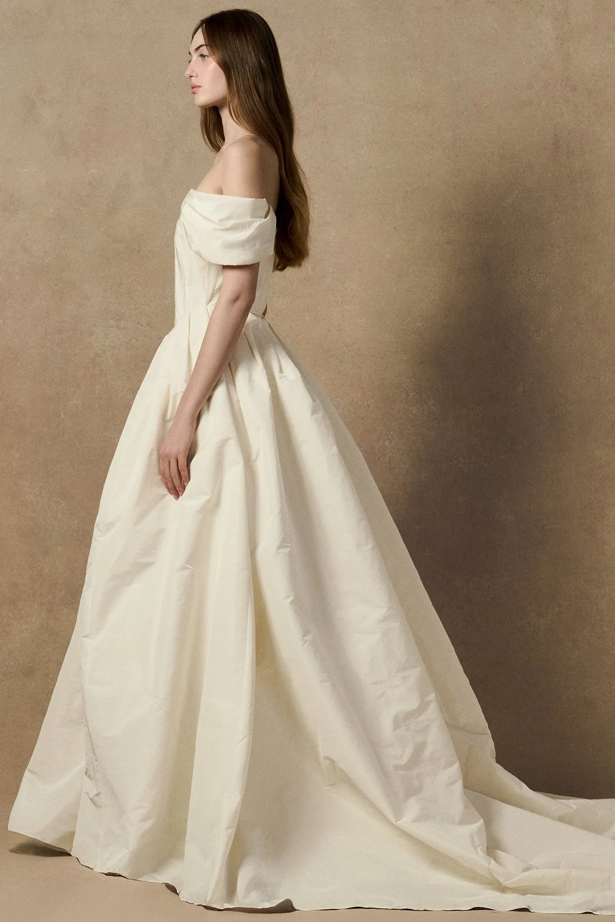 side image of Lubi dress in pleated weightless taffeta, featuring a structured support corset, shown with sleeves and full length gown