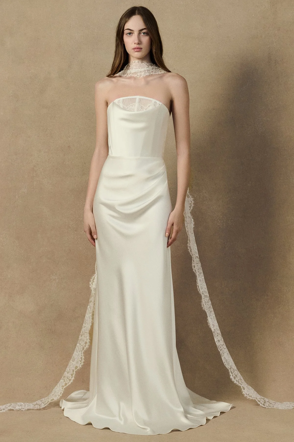 front image of Herah Dress in liquid crepe back satin featuring a cowl neckline, lace trim details, and an draped skirt. worn without sleeves