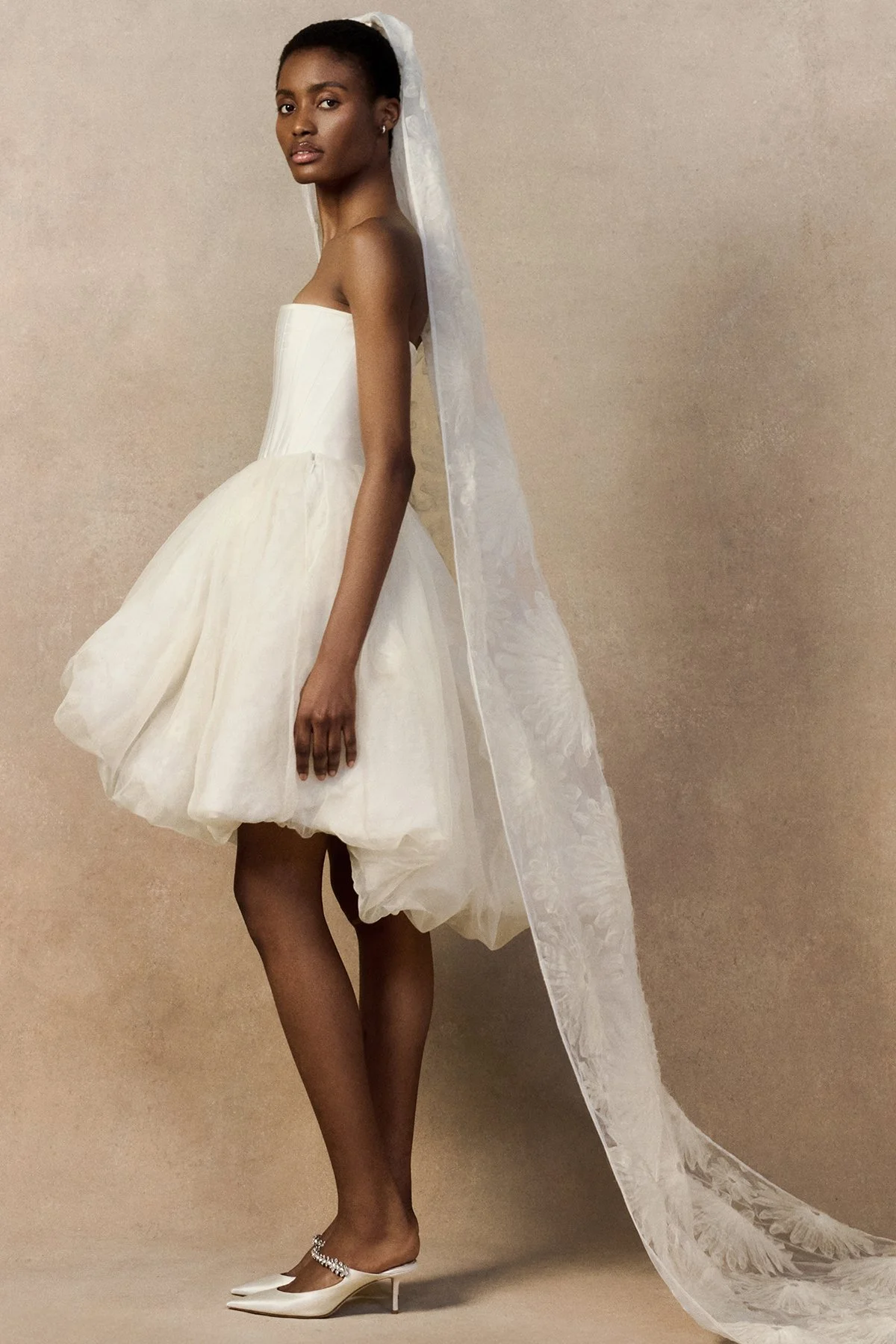 side image of Meg Mini skirt featuring looped daisy motifs in a bubble-shaped silhouette with a high-low hem. worn with fig veil and phoenix corset