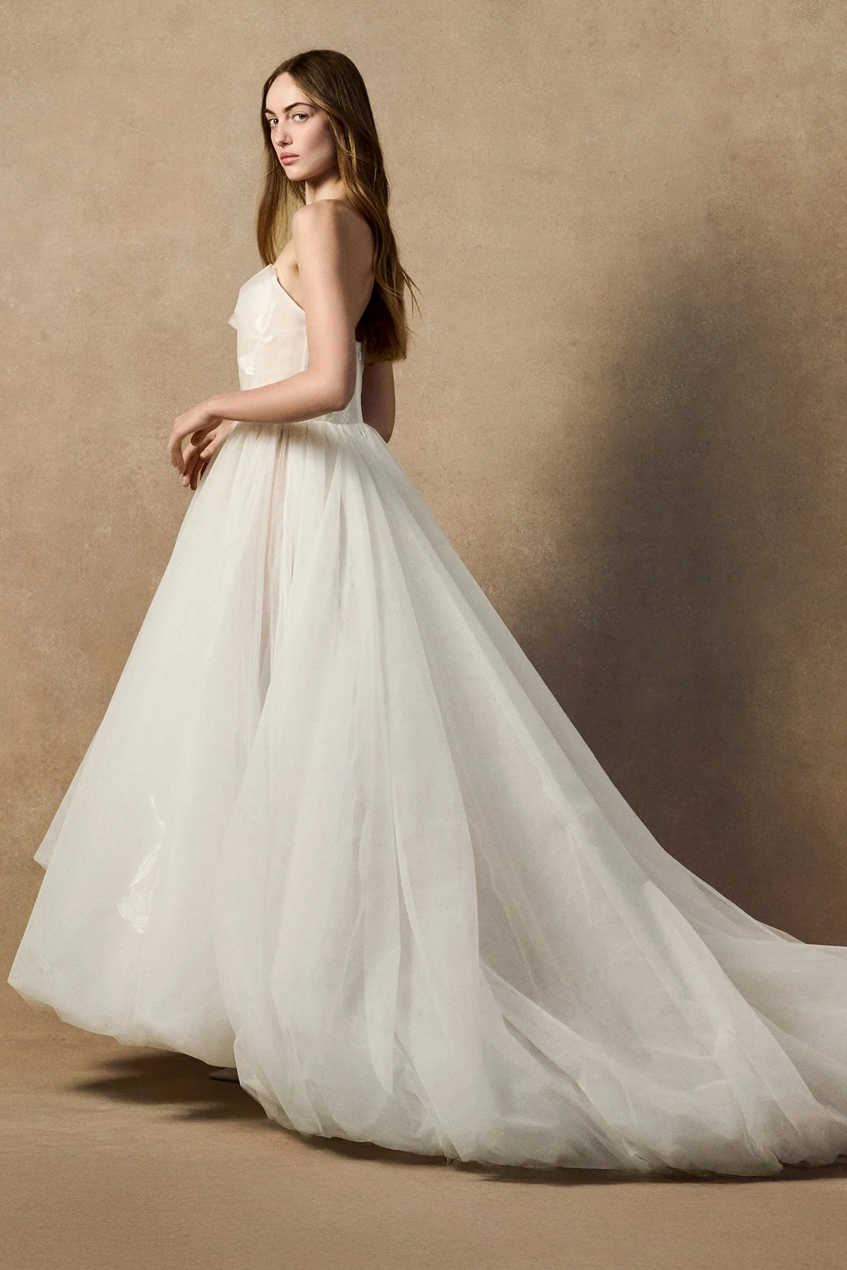 side image of model wearing the Cosmos bridal dress with a sheer exposed corset, hand-stitched echinacea floral embroidery, and a voluminous bubble-hem tulle skirt.