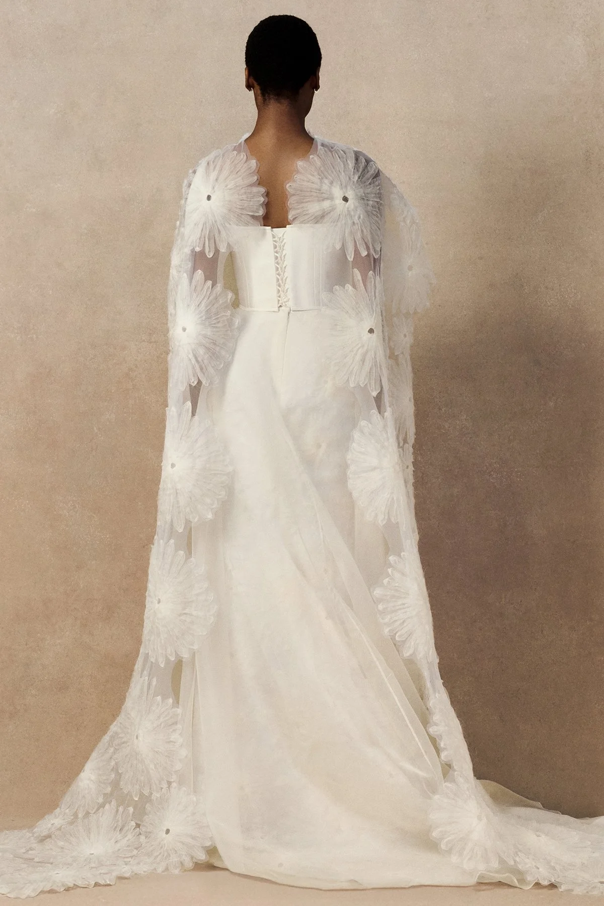 back image of Meg bridal skirt with looped daisies in raw-edged silk organza, and a layered silk organza fit-and-flare skirt. with phoenix corset and fig cape