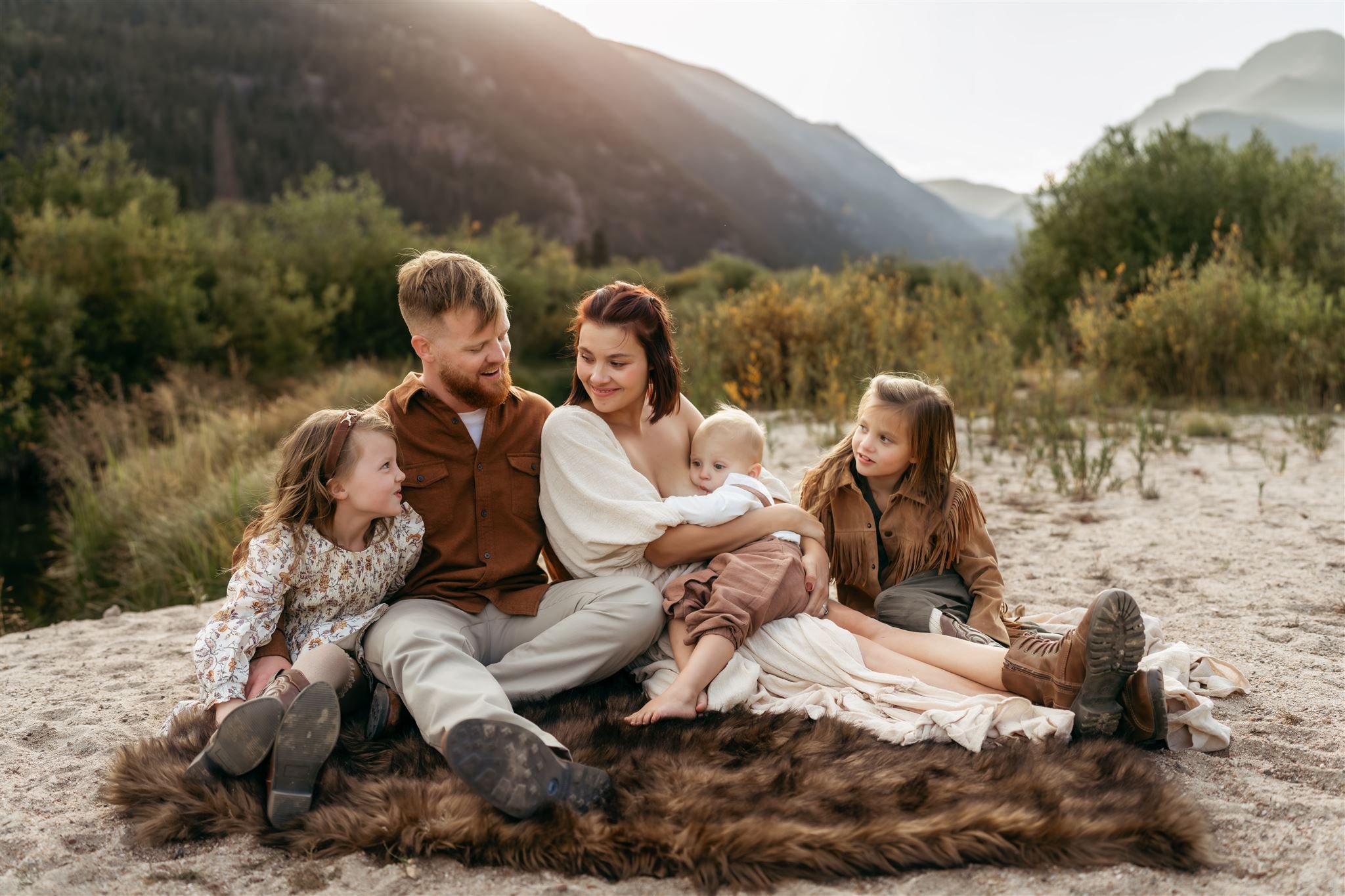Boulder Family Photographer | Family sits together on the sand snuggled on a blanket