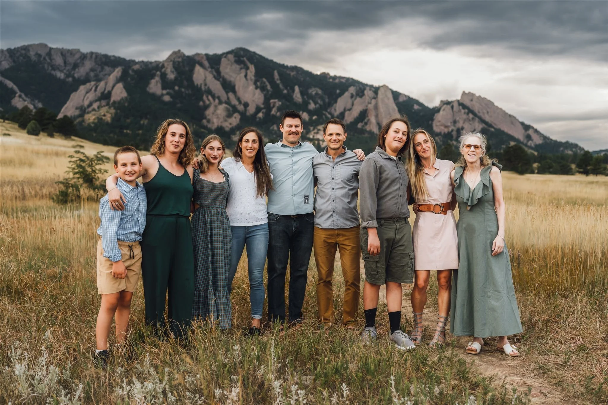 Extended Family Photography in Boulder | Family stands together with arms around each other in front of the flatirons in Boulder