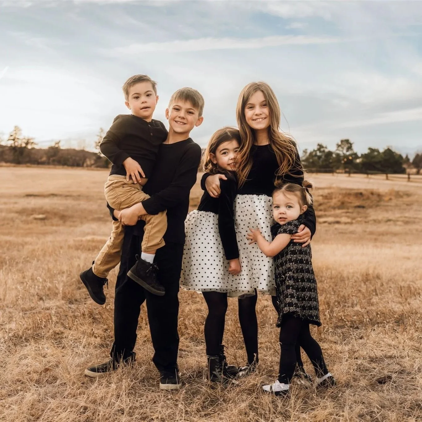 Extended Family Photography in Boulder | Five children stand together, the larger boy holding the younger one the older girl with her arms around the younger ones.