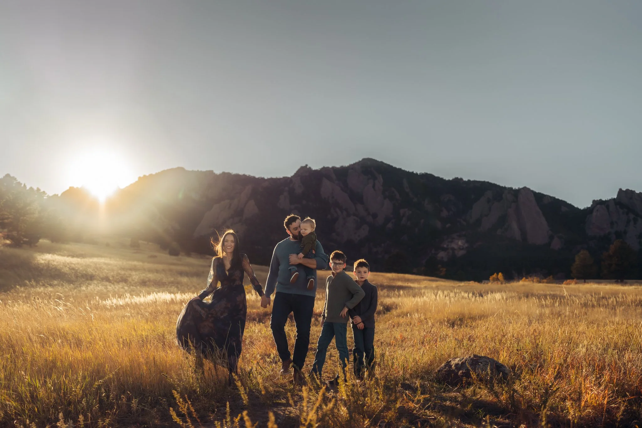 Boulder Family Photographer | Family walks holiding hands across a field with flatirons behind them