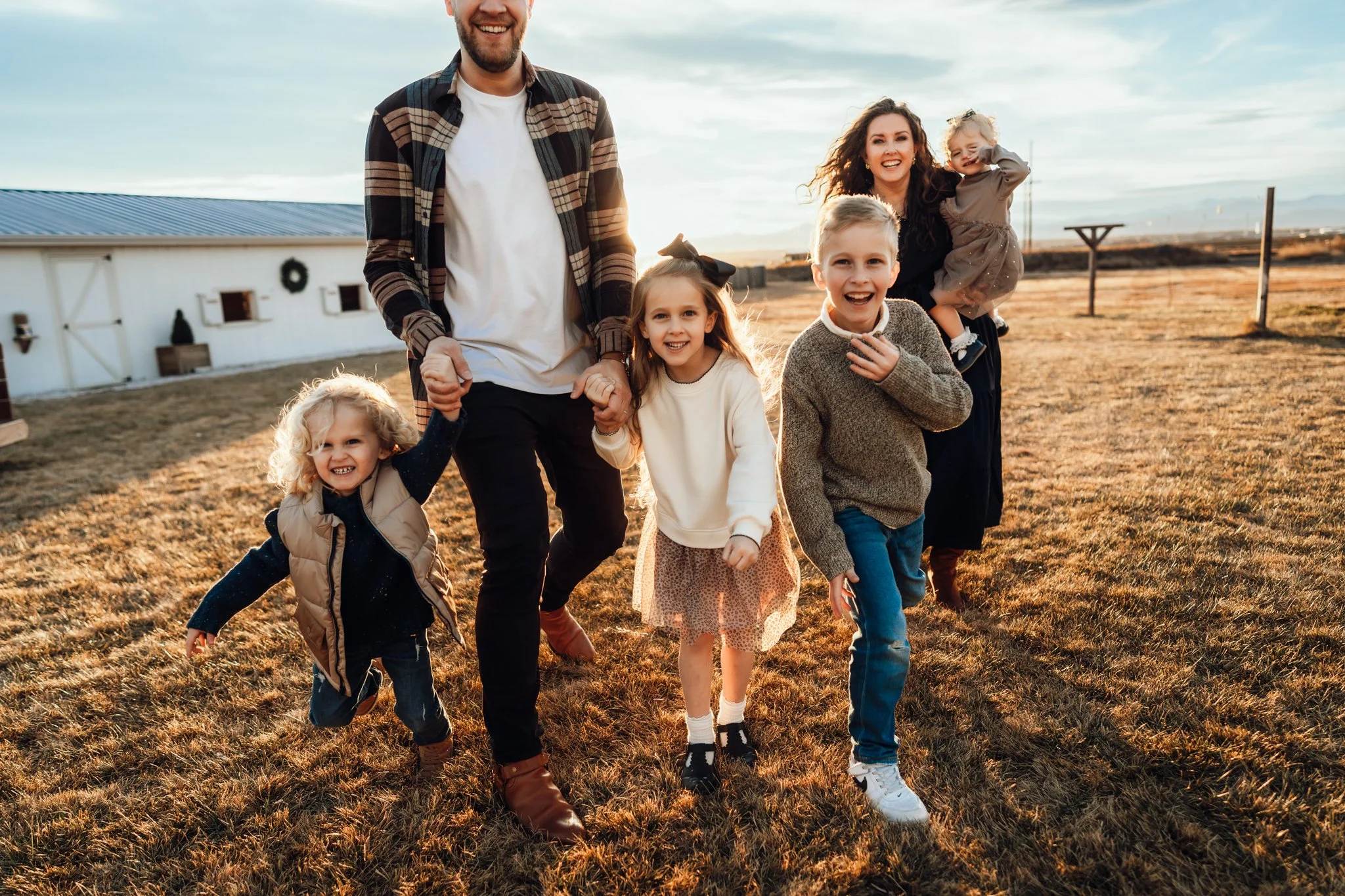 Denver Family Photographer | Family running towards the camera while holding hands in a field