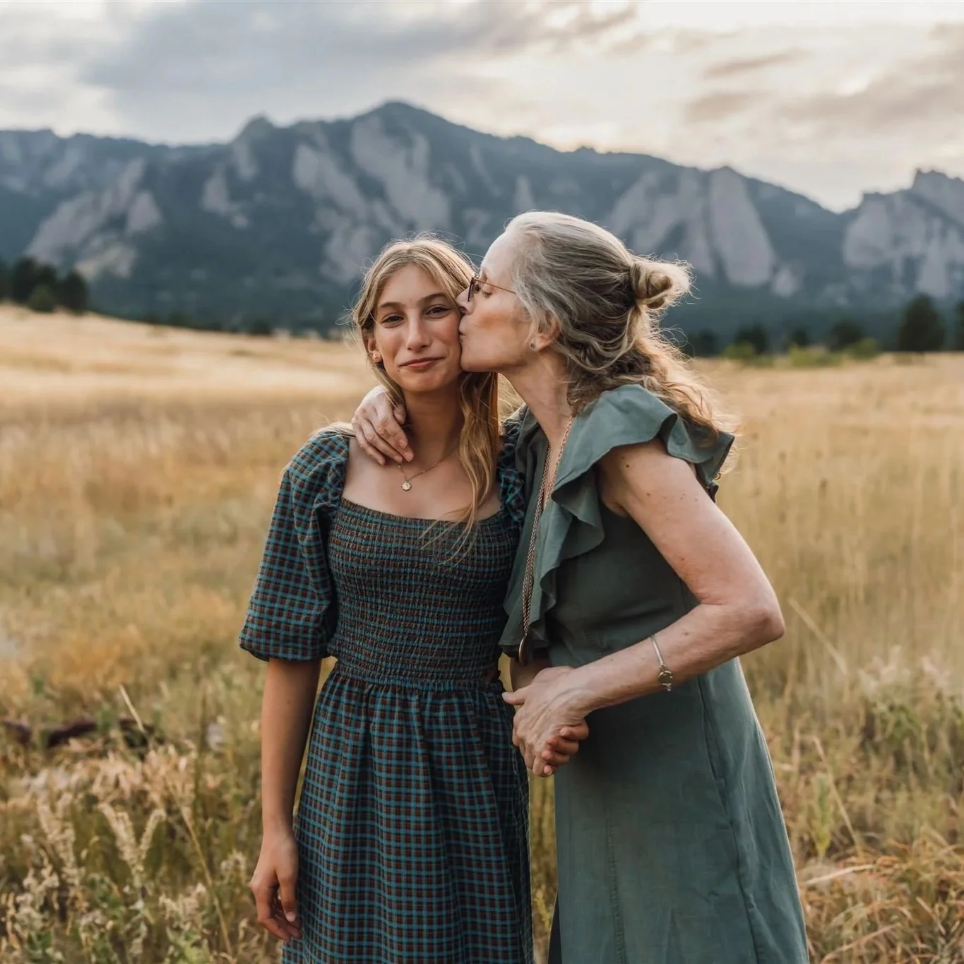 Extended Family Photography in Boulder | Grandmother kisses grandaughter on the cheek in front of the foothills in Boulder