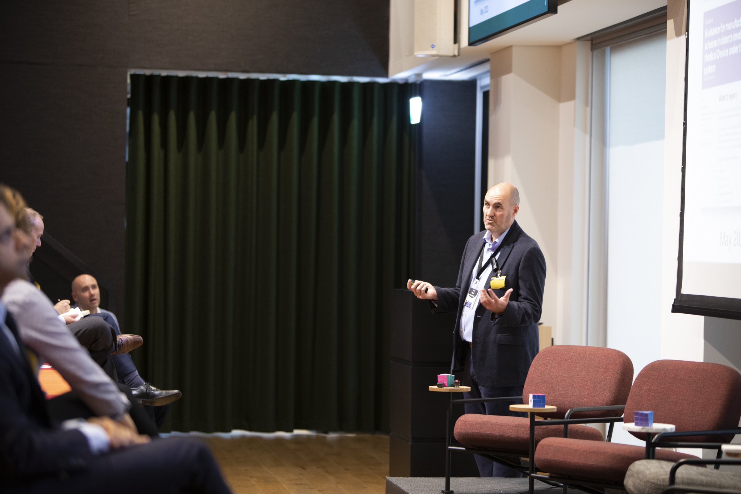 Person giving a presentation in a conference room with seated audience members.