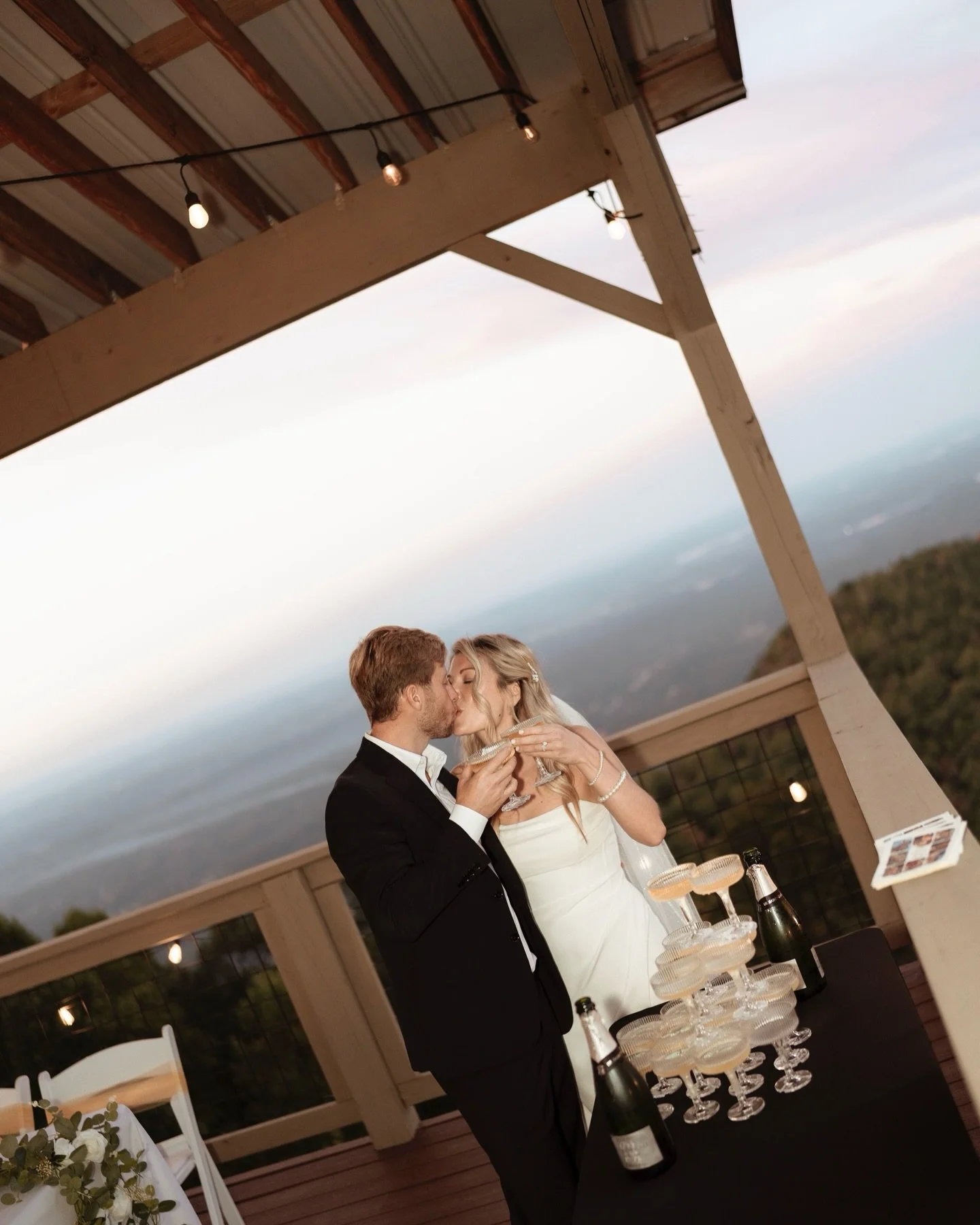Golden hour, champagne towers, and a love that feels like forever. ✨🥂

Capturing this sweet moment as they toasted to a lifetime together &mdash; the mountain views, the soft glow of the string lights, and that just-married magic made it unforgettab