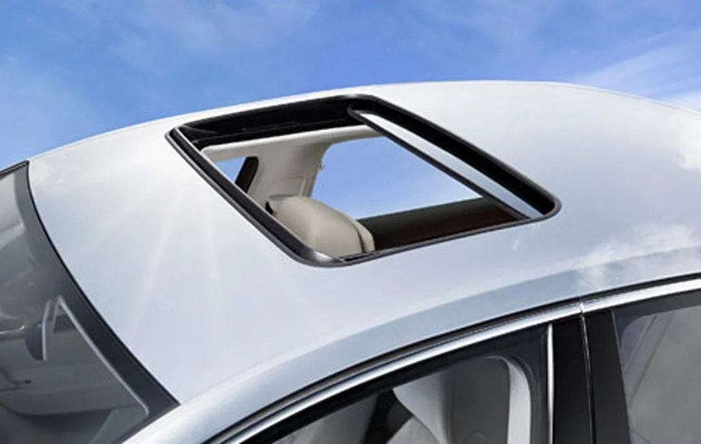 Car with an open sunroof against a blue sky.