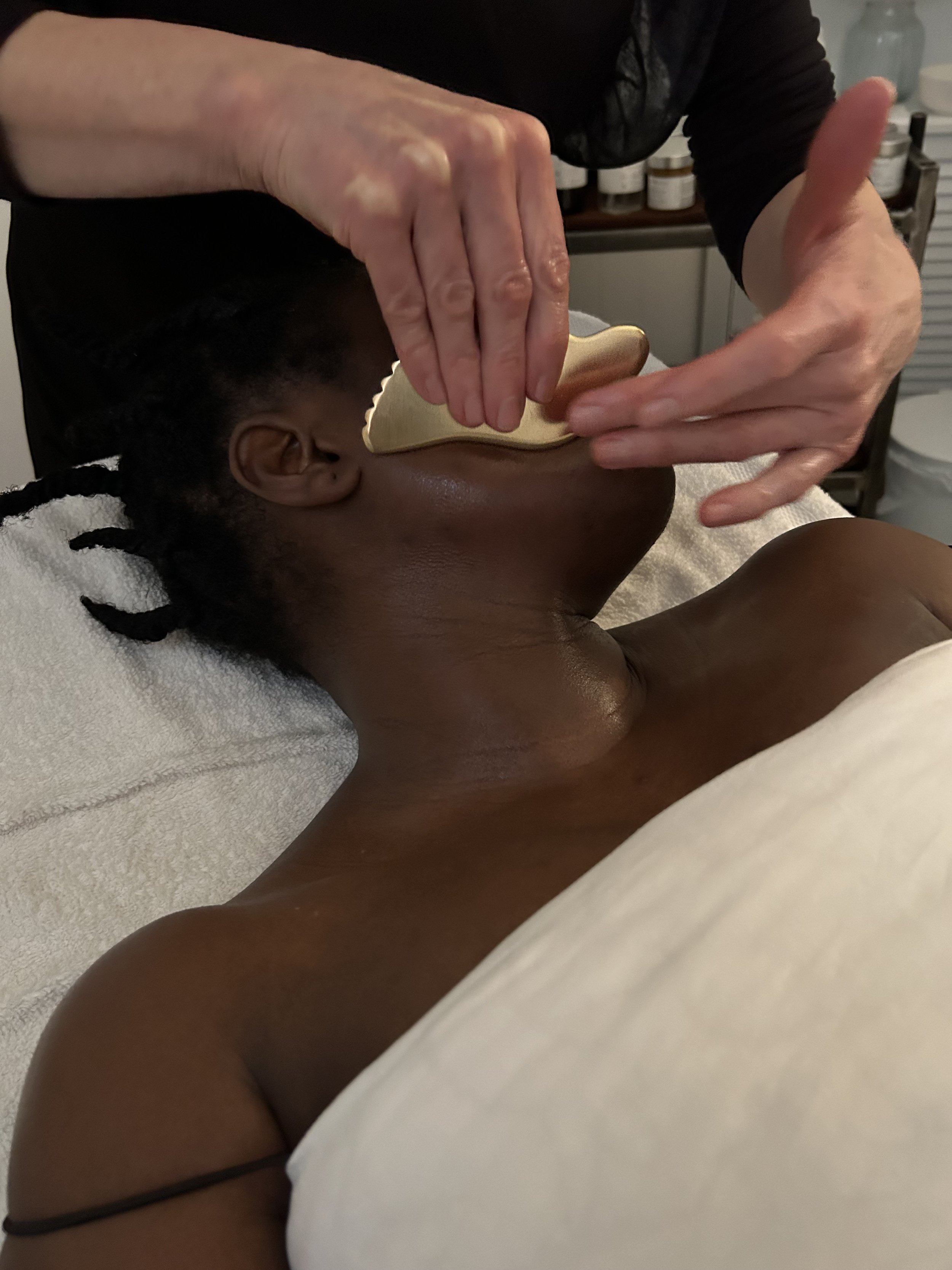 Client receiving a holistic gua sha facial