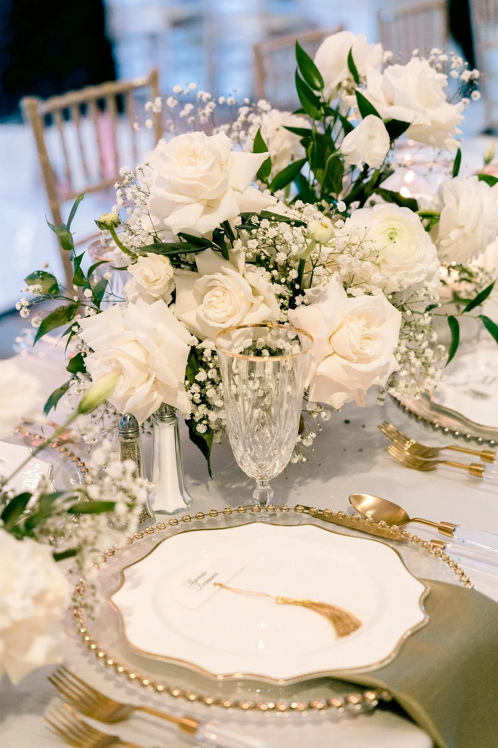 White rose and baby's breath centerpiece in a crystal footed vase with gold charger and flatware, Las Vegas wedding florist reception design