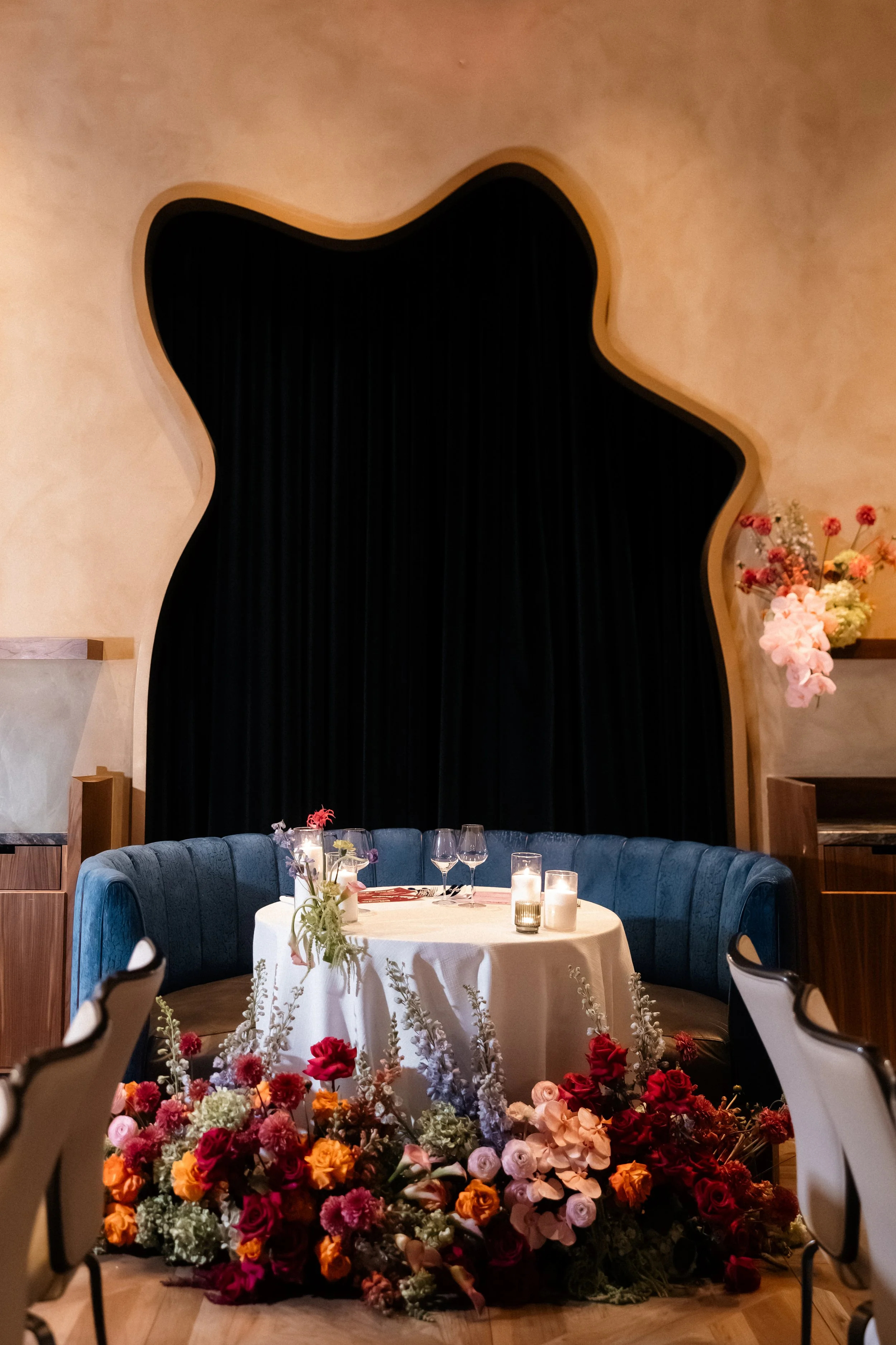 Intimate sweetheart table in a blue velvet banquette with a low floral runner in coral and burgundy, Las Vegas elopement and micro wedding florals