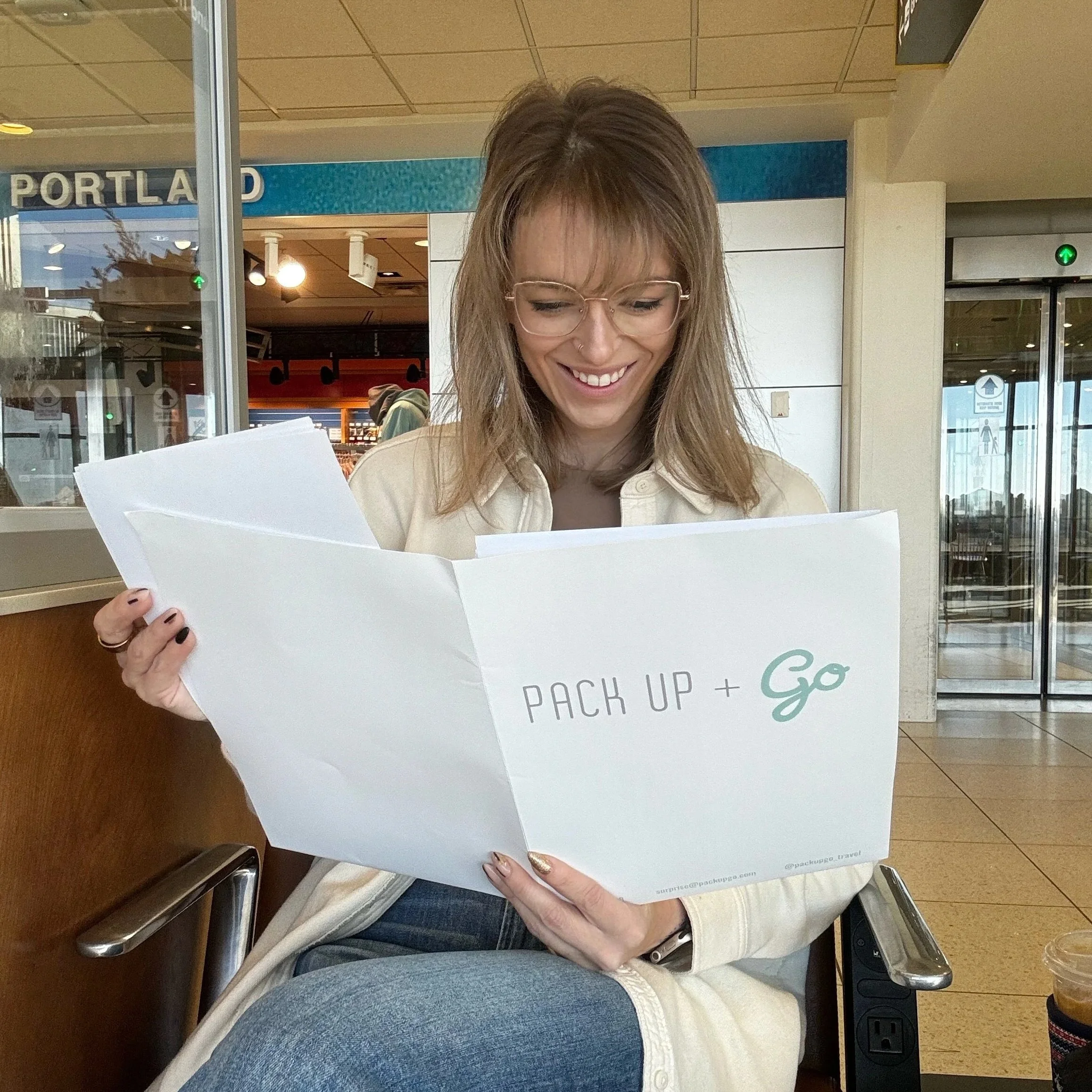 Pack Up + Go traveler reviewing her curated surprise envelope contents at the airport