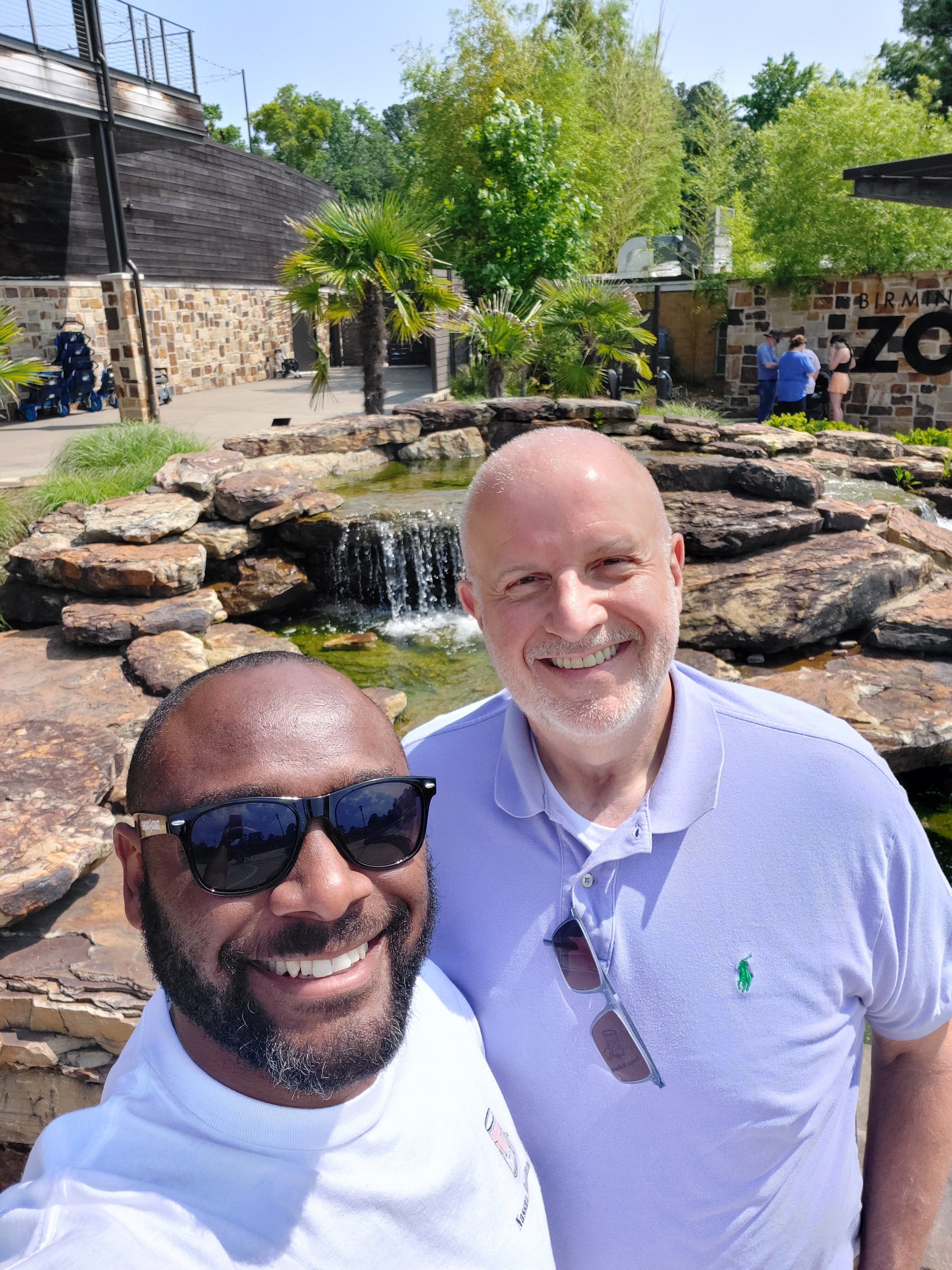 two travelers pose in front of a waterfall