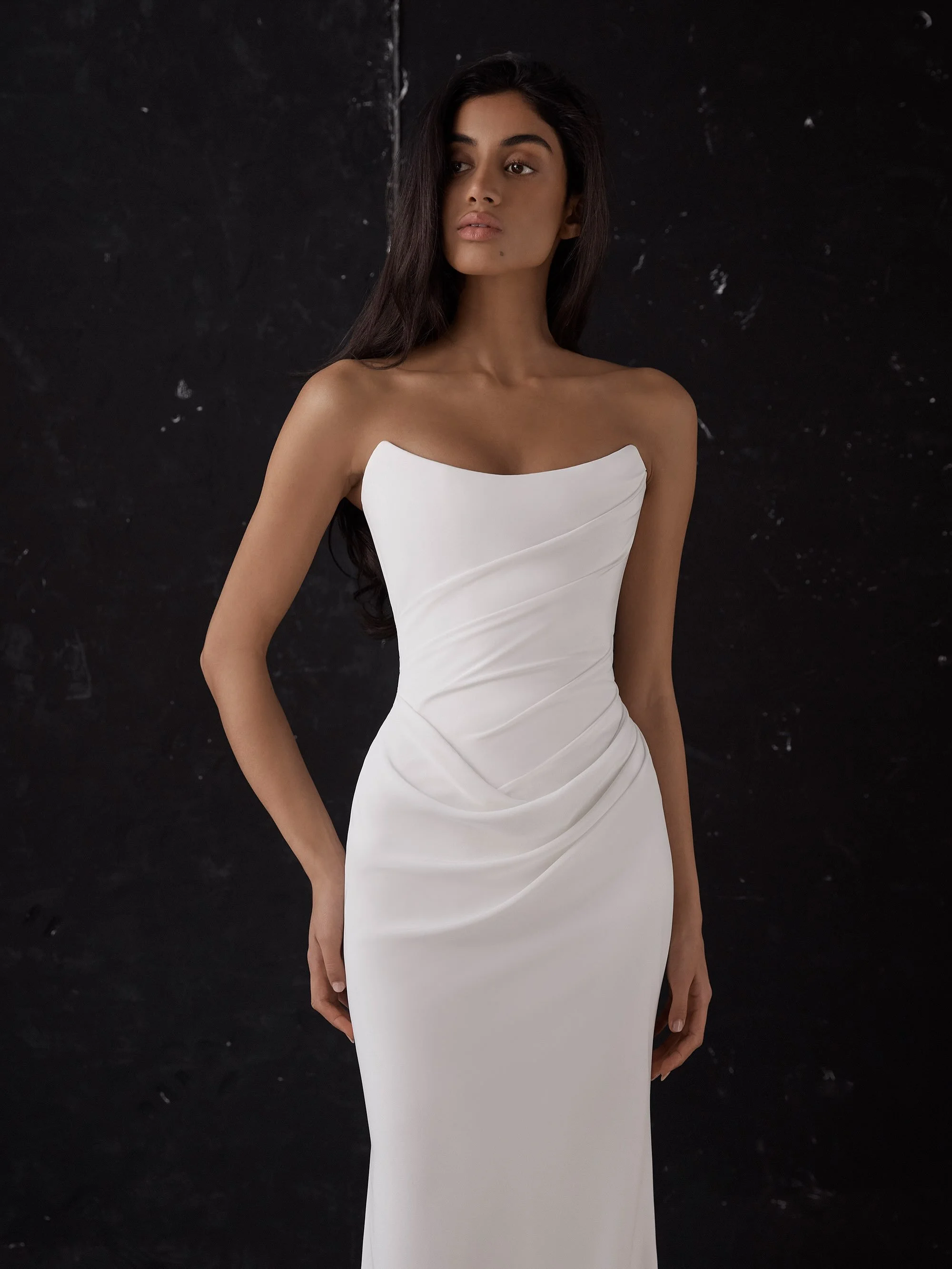 ARCHER by KYHA 

Draping becomes an art form in Archer. Crafted from a matte triacetate, a structured, scoop neckline bodice cinches the waistline and a fit and flare skirt celebrates the female form. But the star of the showstopping Archer gown is i