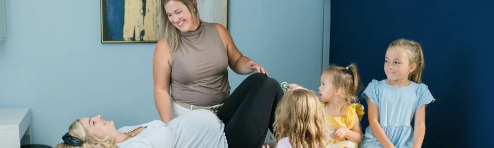 Postpartum mom with kids being treated in phyiscal therapy for postpartum rehab