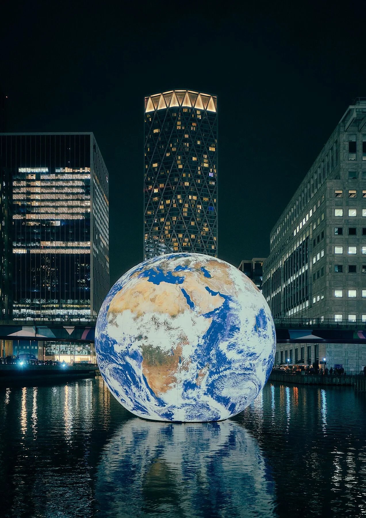 High-quality Photo Print of a glowing Planet Earth sculpture floating in a wharf in Canary Wharf, London