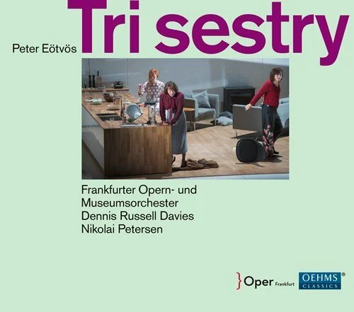 Cover of a music score book titled "Tri sestry" by Peter Eötvös, featuring a photo of three people in a modern kitchen, one cooking, one at the countertop, and one walking with a suitcase.