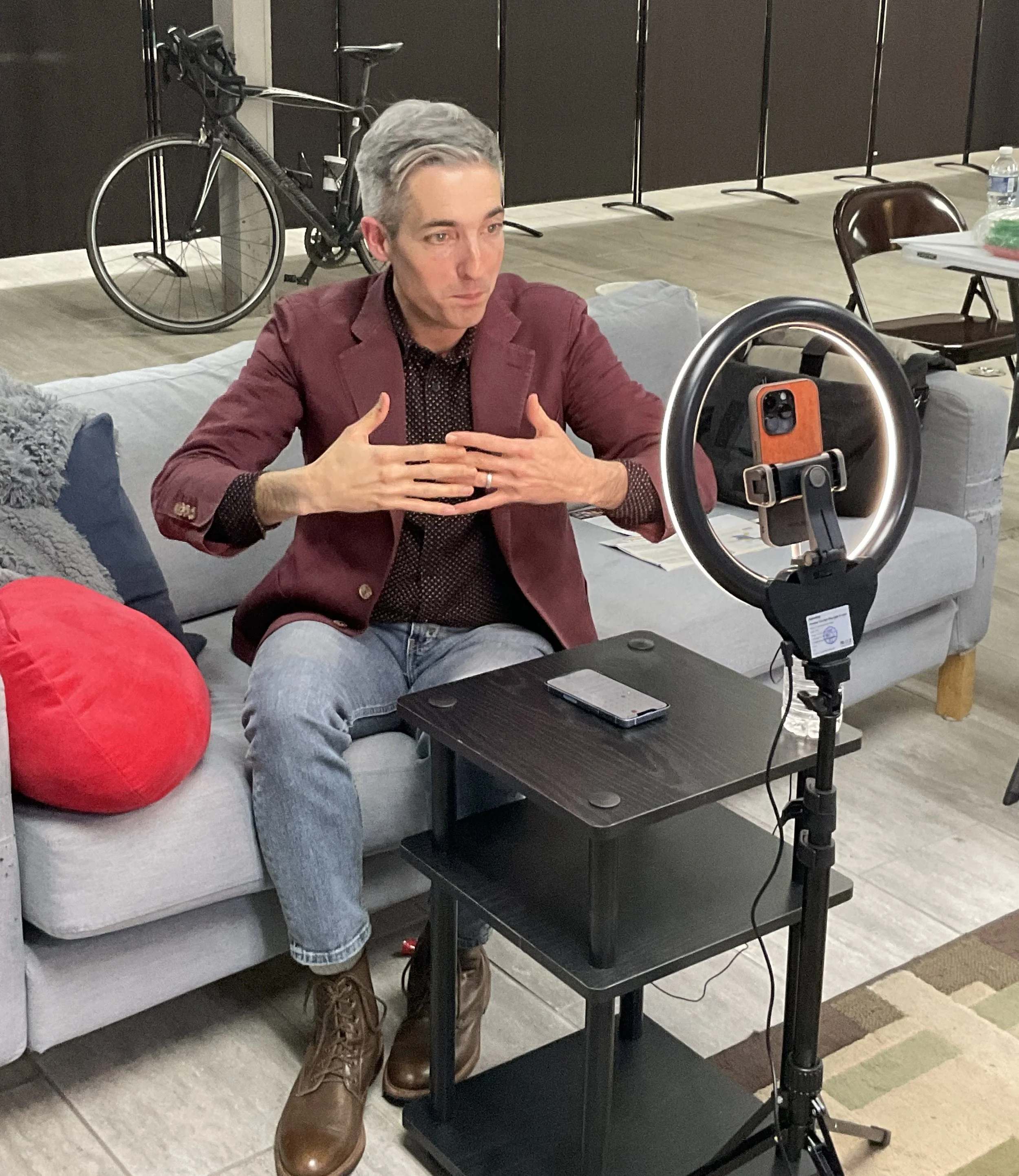 Daniel sits on a couch recording video answers