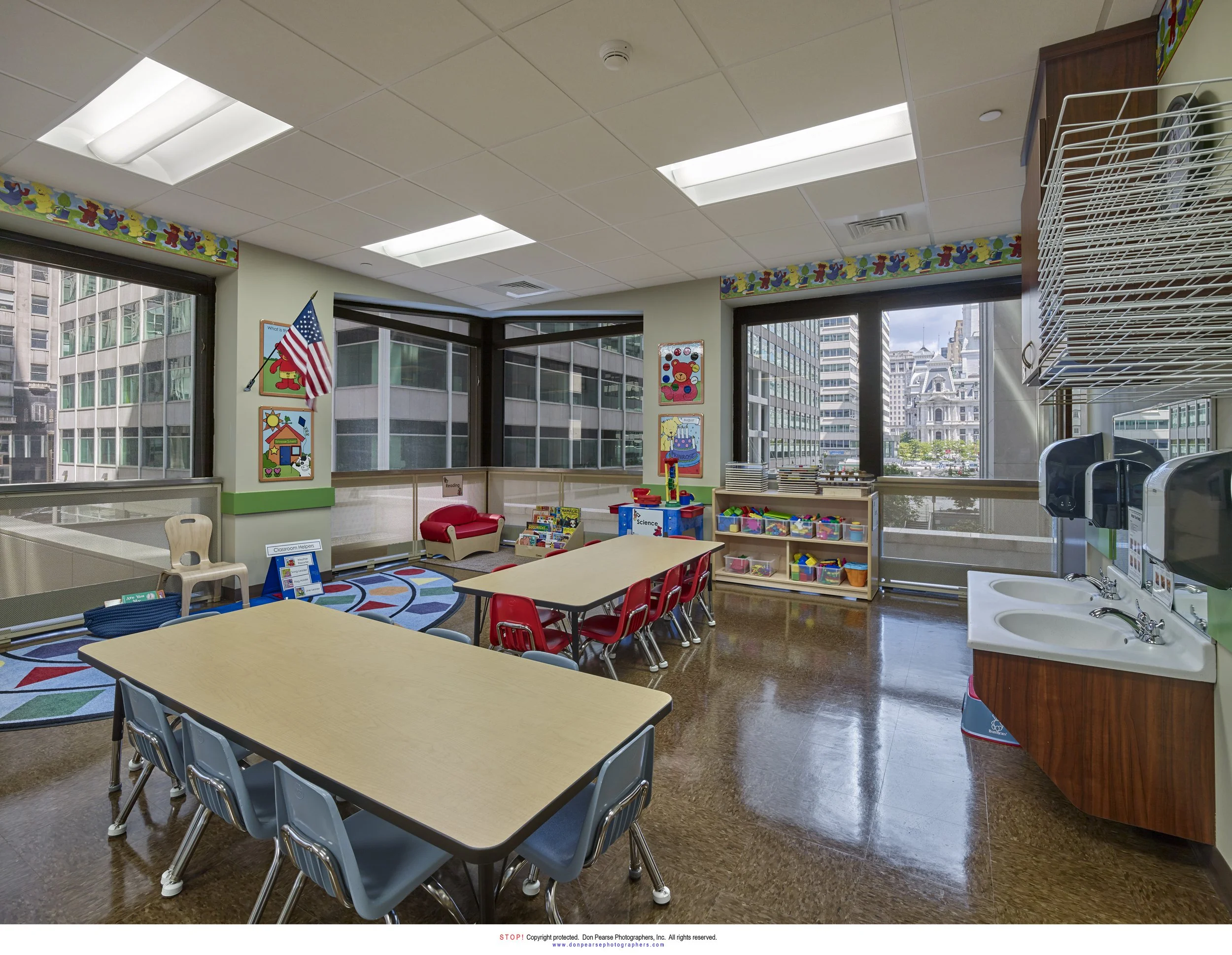 Classroom in a high-rise building with large windows, colorful decorations, children's furniture, and educational toys.