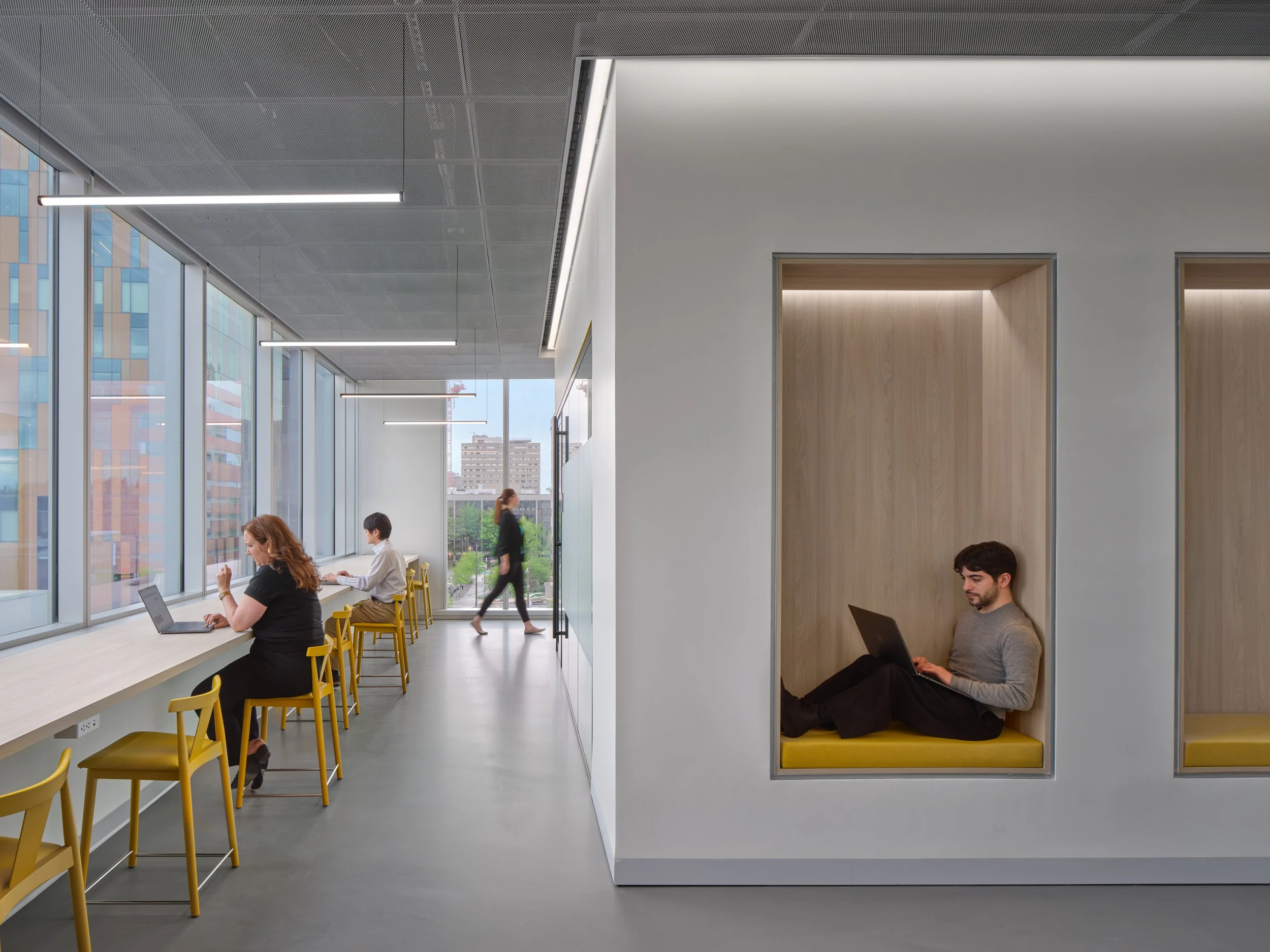 Office space with private inset cubicle seating to maximize workspaces. Additional bar height seating for coworking space.