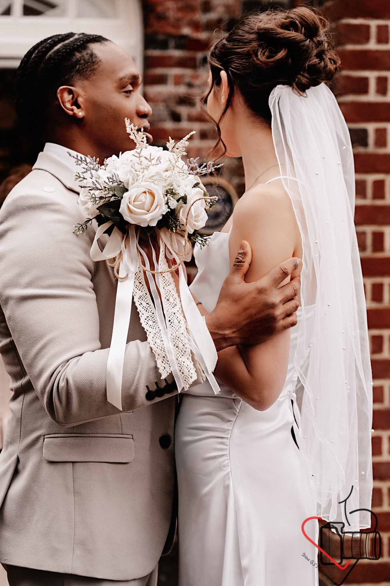Couple during their wedding ceremony, facing each other close with tender expressions, one holding a bridal bouquet, Portsmouth Register Office, Milldam House.