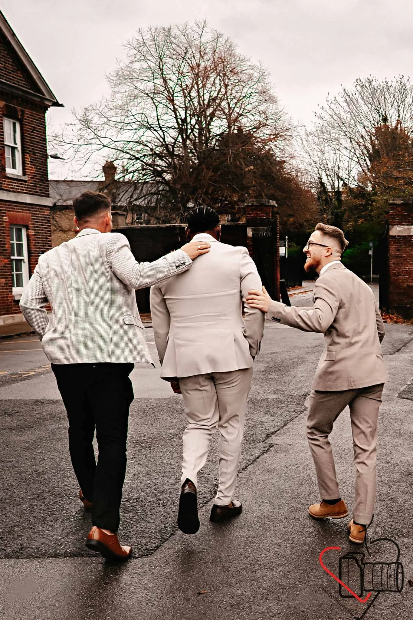 Three men in suits walking together along a wet street on a cloudy day, with trees and brick buildings in the background. Portsmouth Register Office, Milldam House.