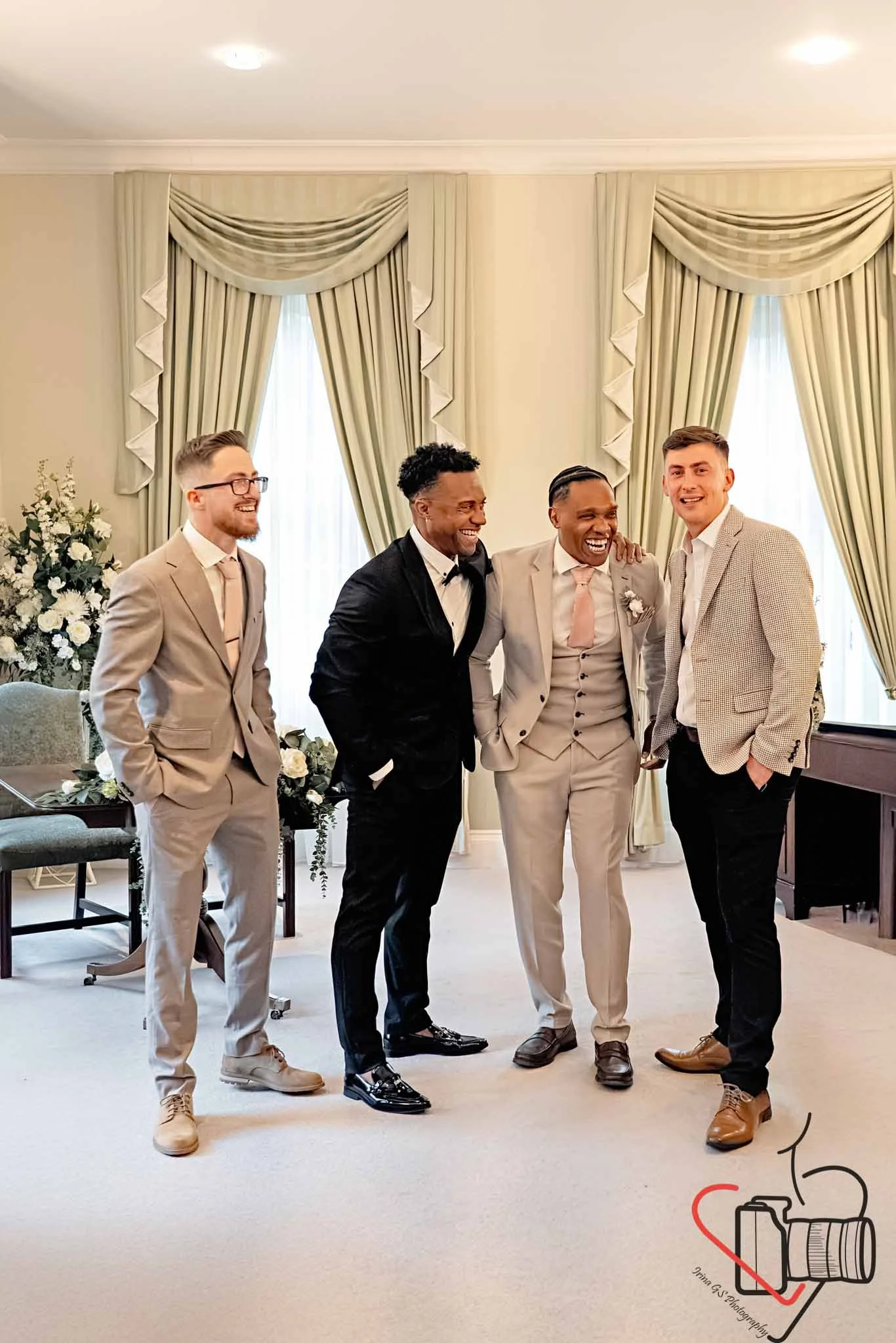 Groom with his friends standing in a room with elegant curtains, smiling and laughing, dressed in formal attire for a celebration or wedding. Portsmouth Register Office, Milldam House.