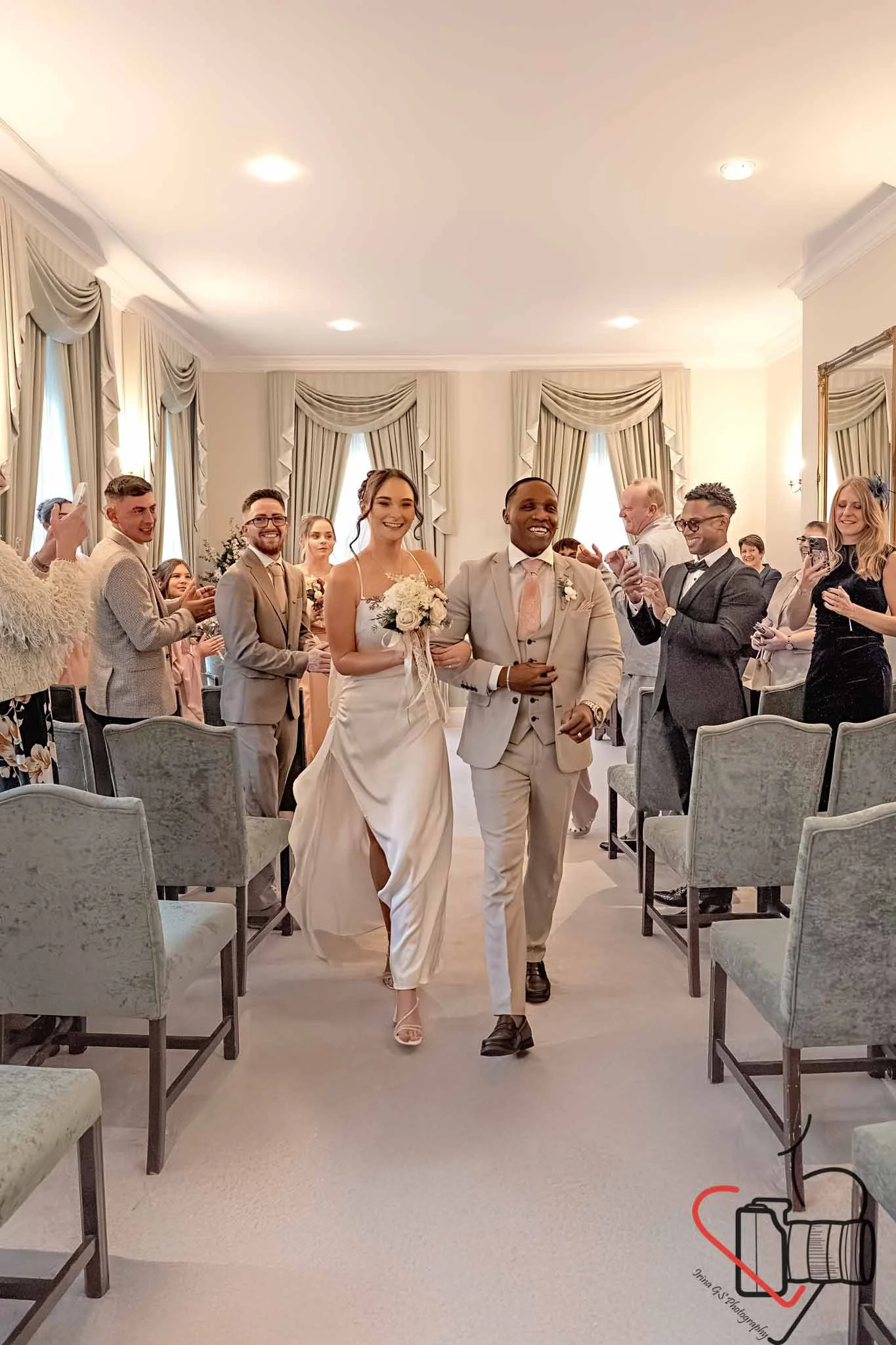 Happy bride and groom walking down the aisle at their wedding ceremony, surrounded by friends and family taking photos and celebrating. Portsmouth Register Office, Milldam House.