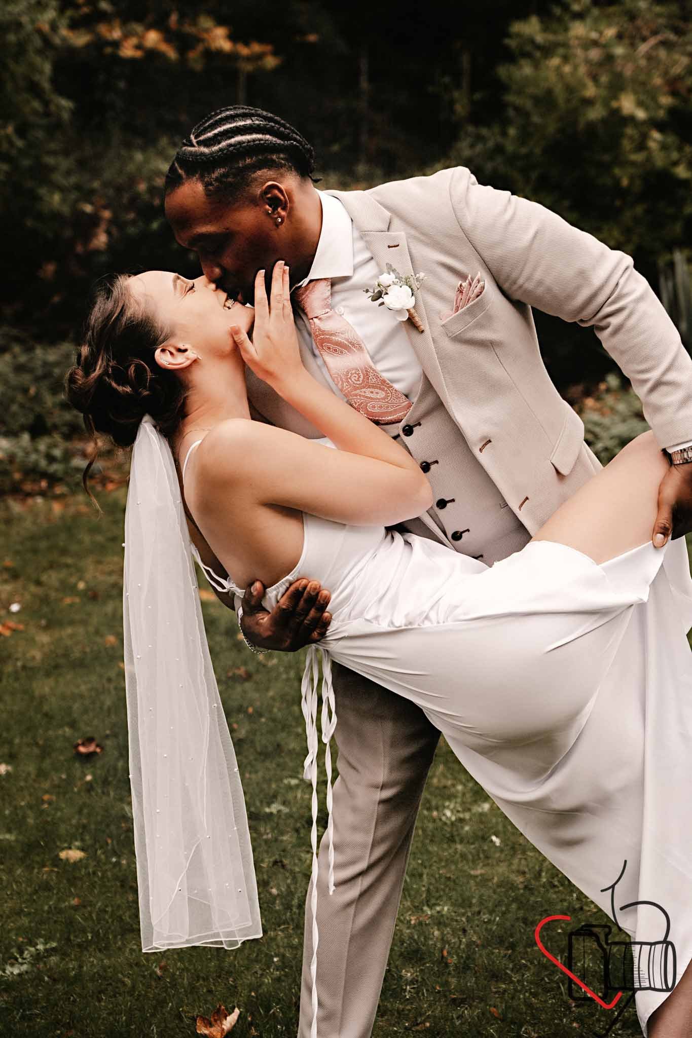 A newlywed couple sharing a romantic dance outdoors, with the groom dipping the bride and both gazing into each other's eyes, surrounded by a natural, green background. Portsmouth Register Office, Milldam House.