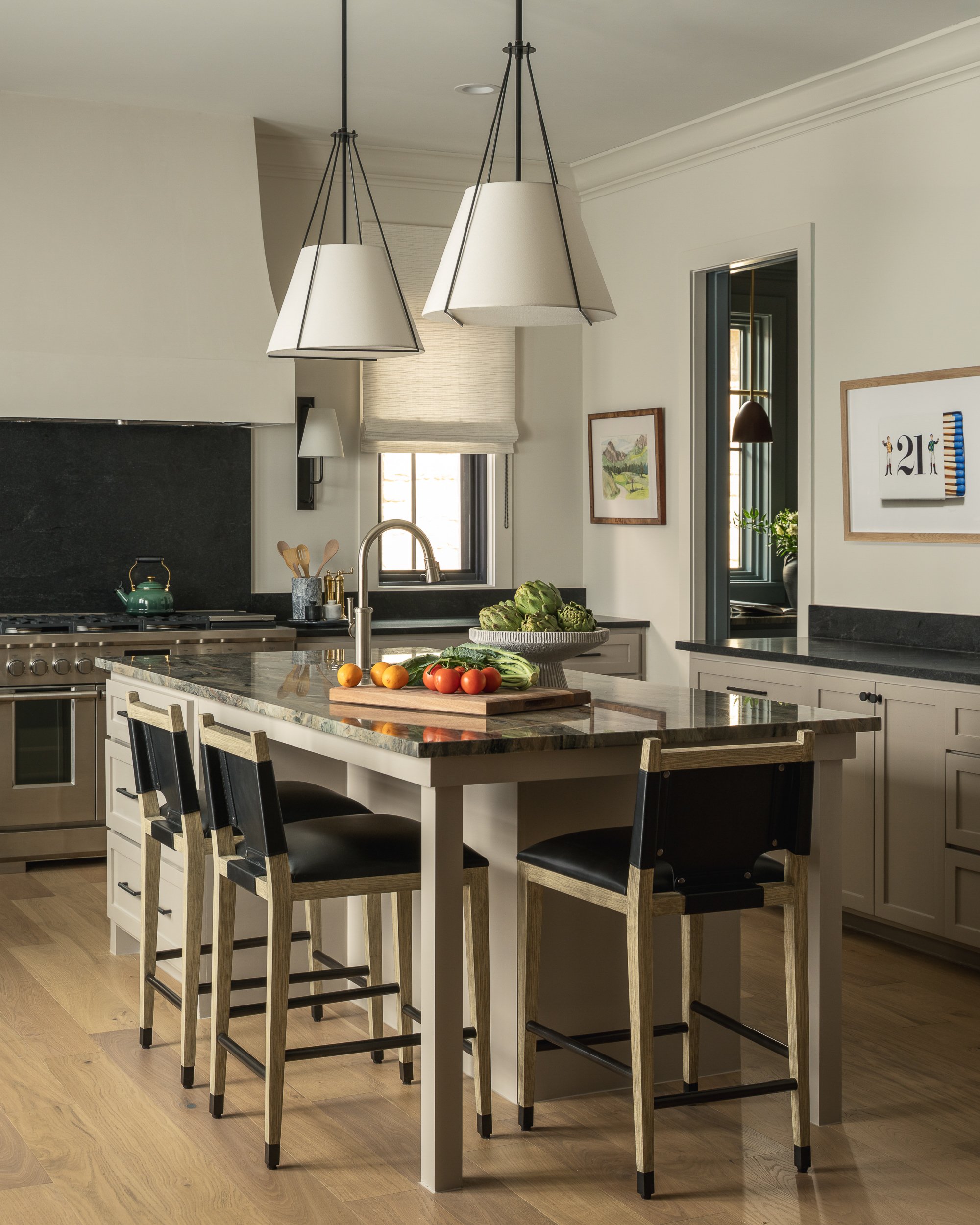 Modern kitchen with island countertop, cabinetry, and hanging pendant lights. Fruits and vegetables on the island.