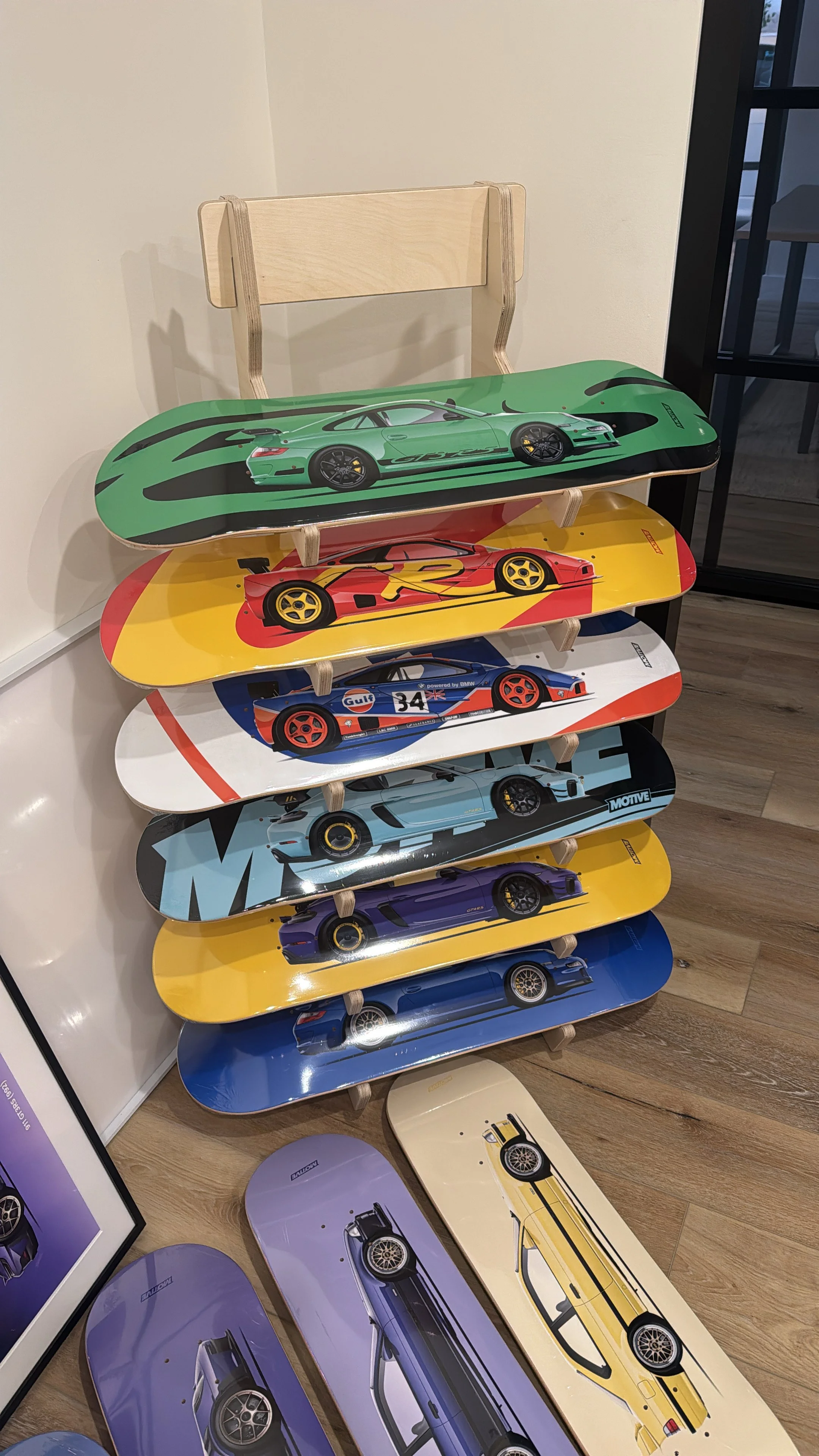 Stacked skateboards decorated with images of sports cars in various colors, including green, red, blue, purple, and yellow.