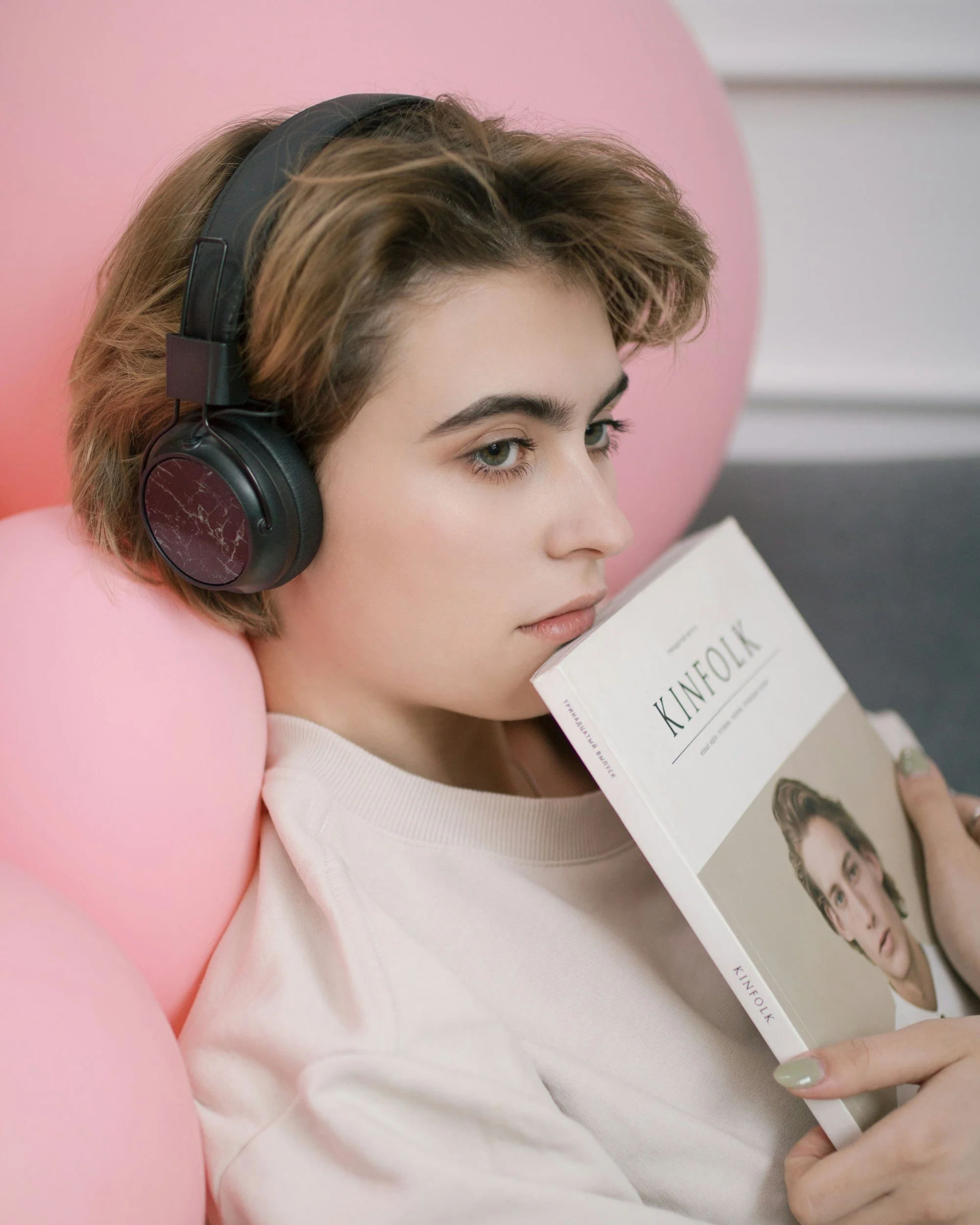 femme wearing headphones and holding book