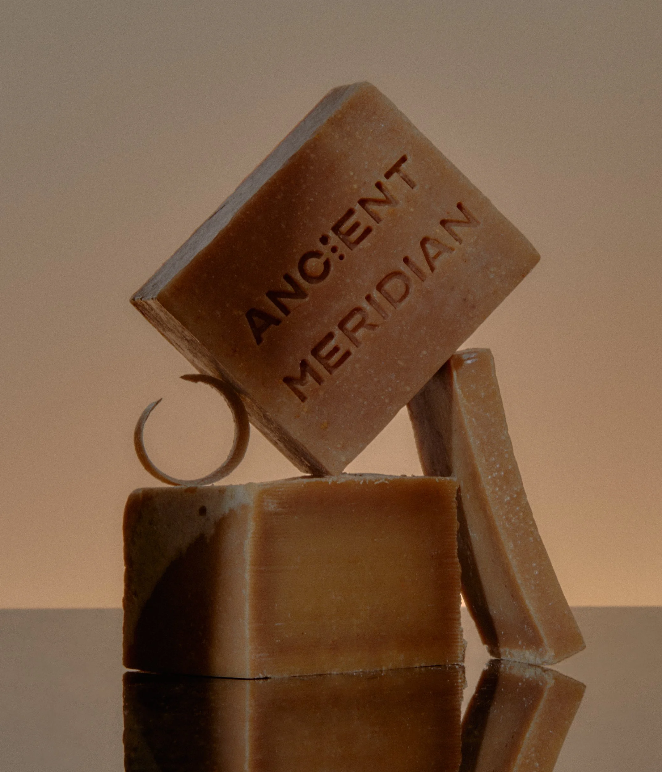 Three bars of soap balance on each other, with one also having a small ring, against a neutral background.