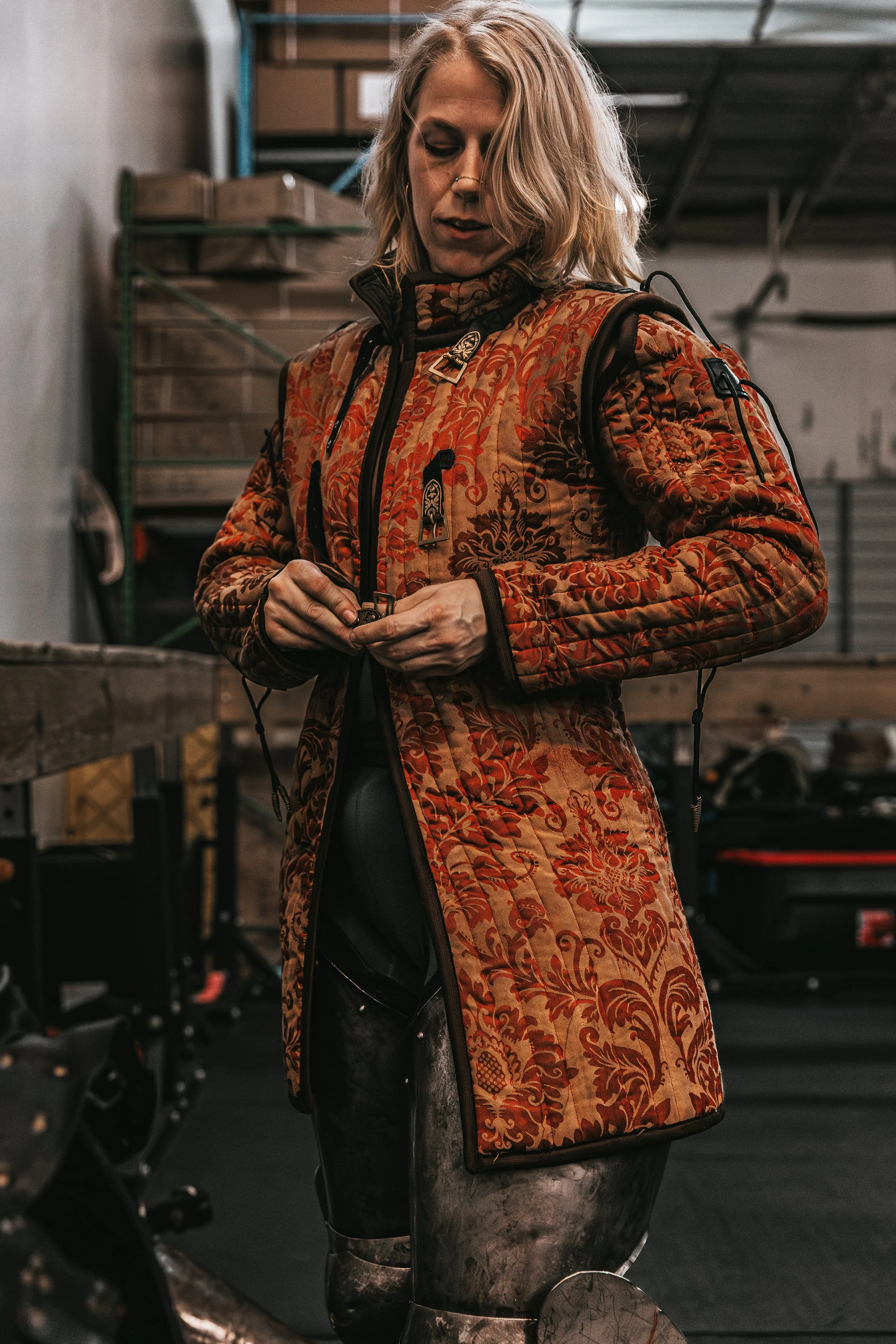 Environmental portrait of a woman wearing a patterned jacket in an industrial workshop setting.