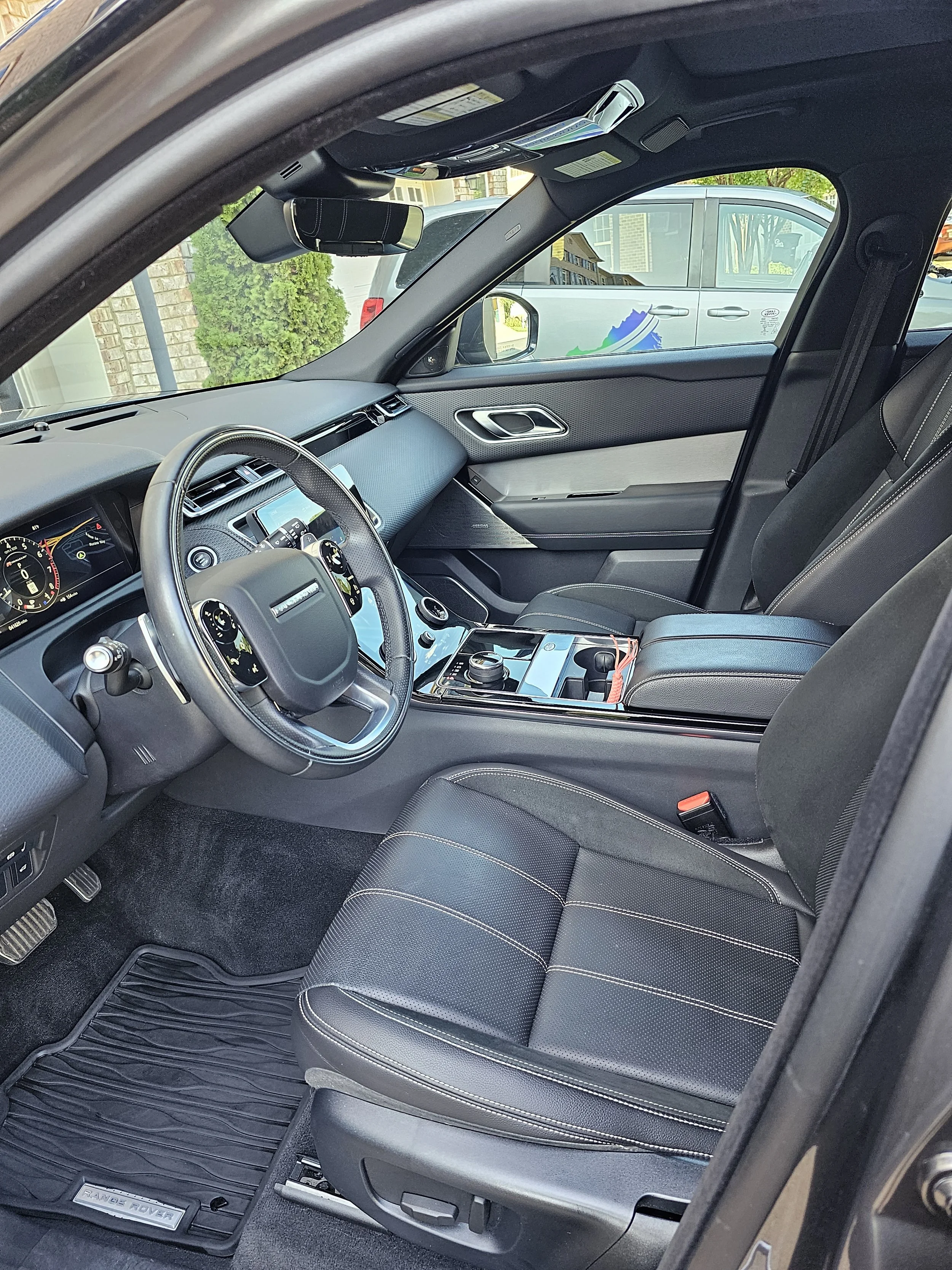 Inside view of a Land Rover Range Rover vehicle showing the front passenger seat, dashboard, steering wheel, and floor mat.