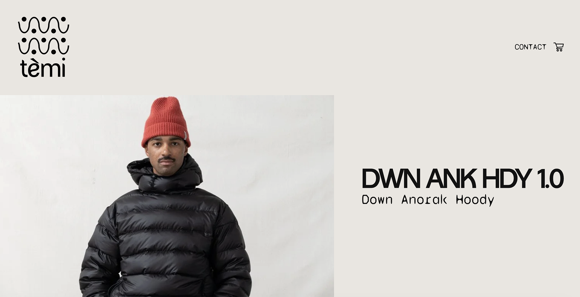A man wearing a red beanie and black Down Anorak hoodie, standing against a plain white background.