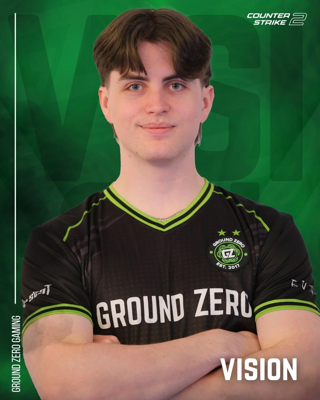 Young man in Ground Zero Gaming esports jersey with crossed arms, standing against a green backdrop with gaming branding.