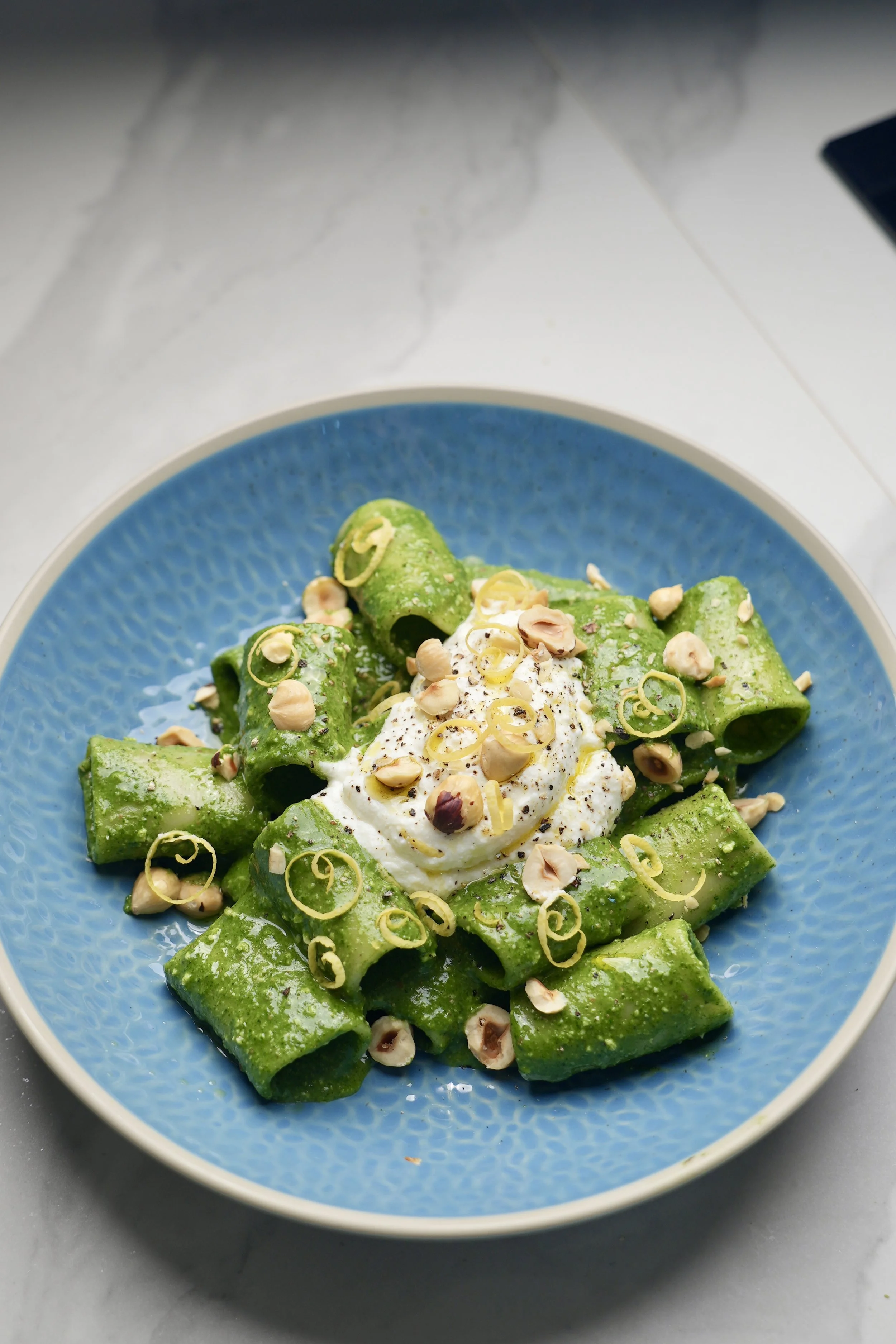 Vibrant green pesto with leafy greens, pasta and ricotta with hazelnuts