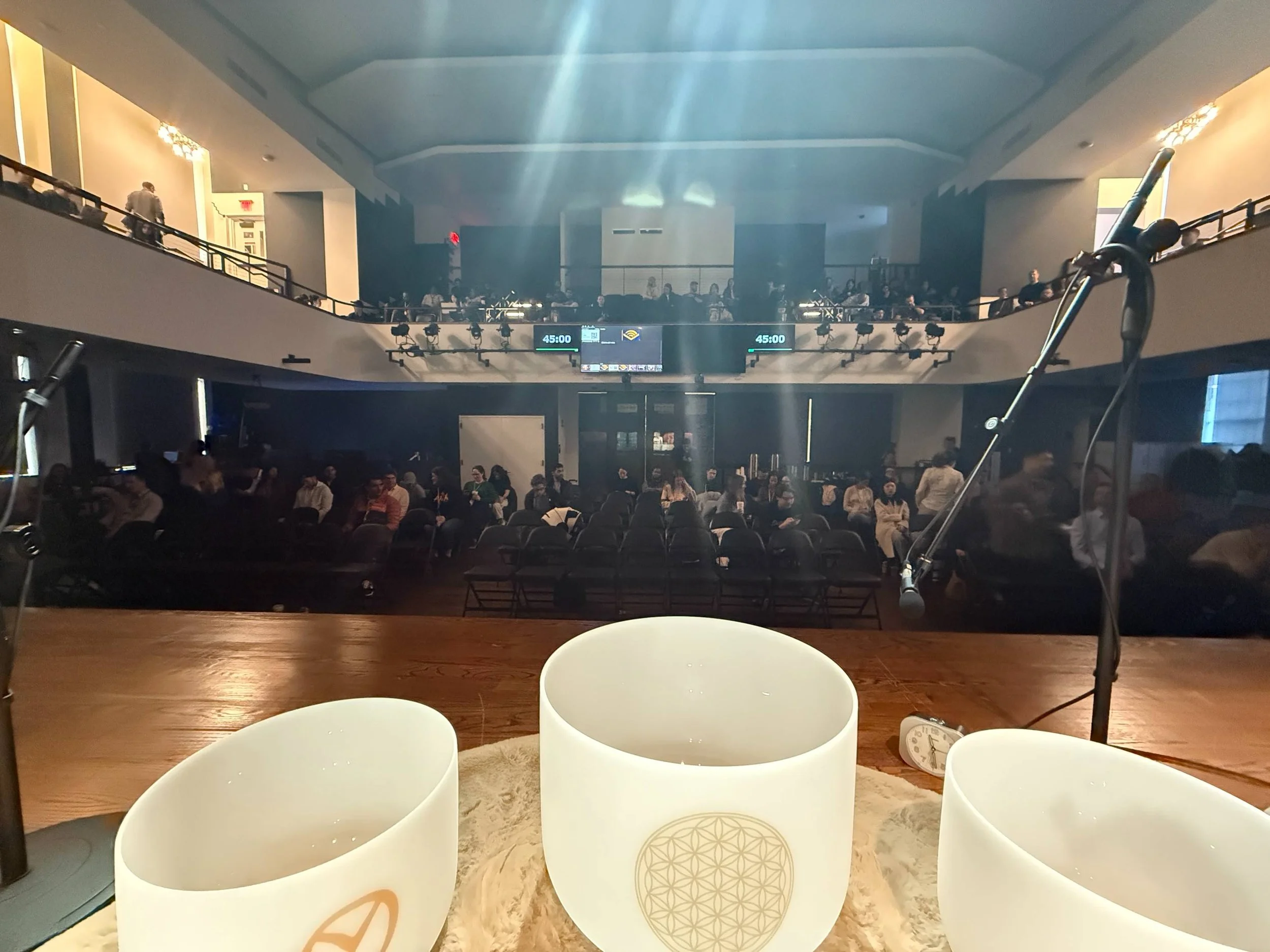 Crystal singing bowls set up on stage during a large-scale corporate sound bath for Audible, with attendees seated in an auditorium.