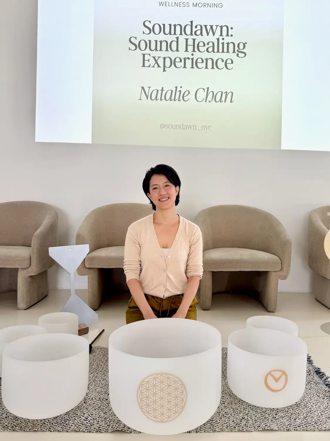 Natalie Chan seated with crystal singing bowls in a lounge setting, ready for a mid-sized corporate sound bath in NYC.